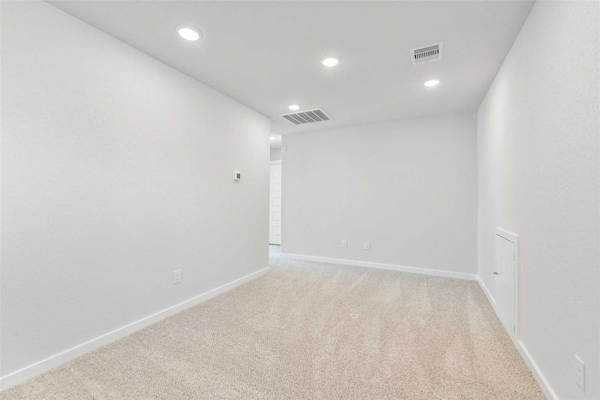 Spacious empty bedroom with white walls, recessed lighting, beige carpet in Davidson Homes Blanco E, Magnolia, Texas