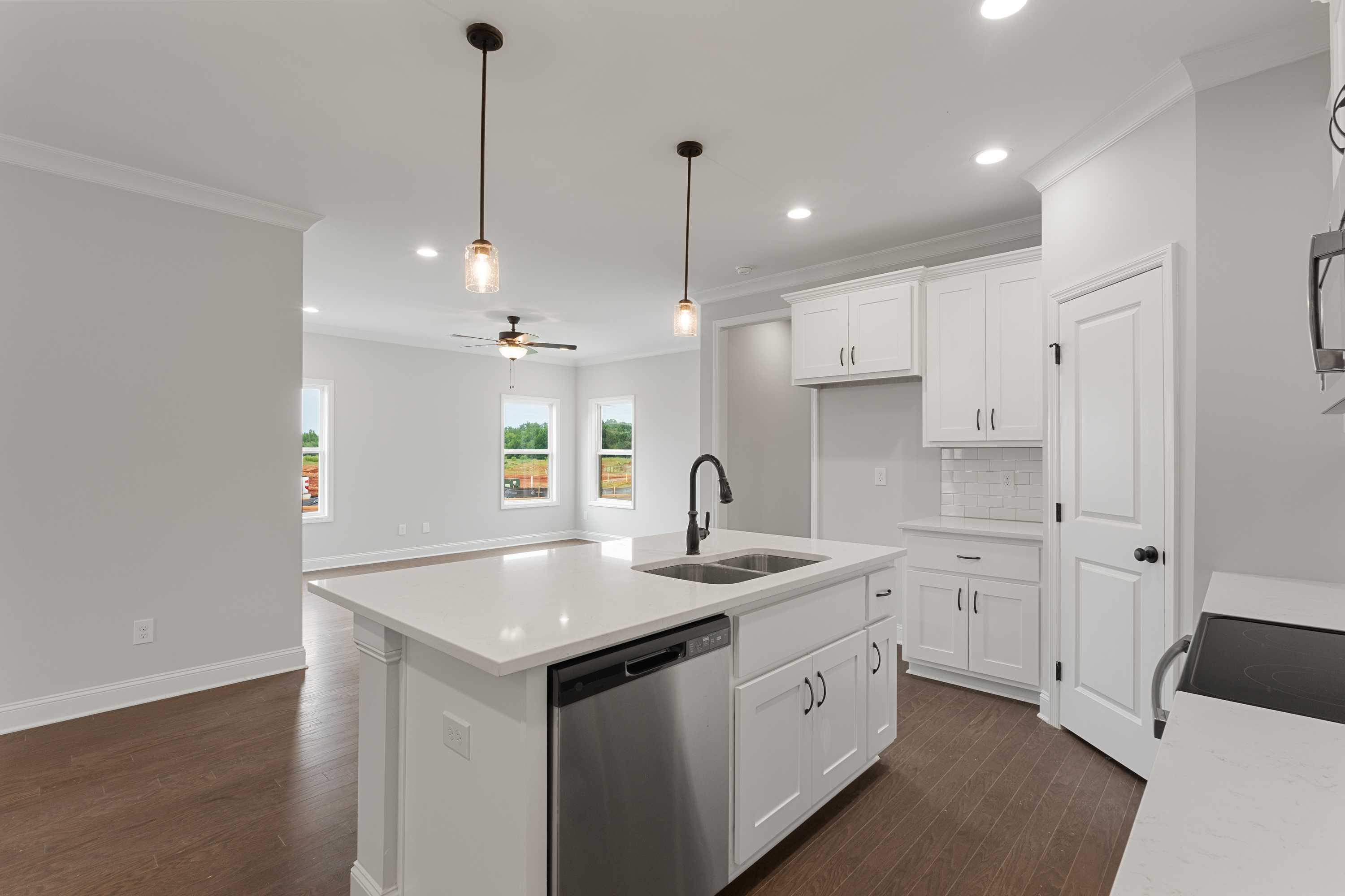 Spacious open-concept kitchen in The Copeland with white cabinets, quartz island sink, stainless appliances, and hardwood floors