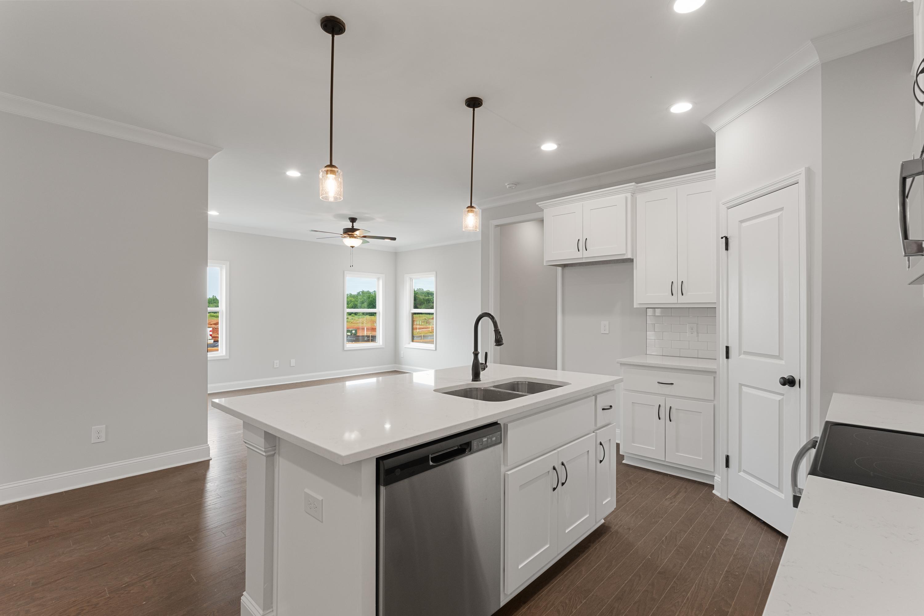 Spacious open-concept kitchen in The Copeland with white quartz island, stainless sink, and hardwood floors