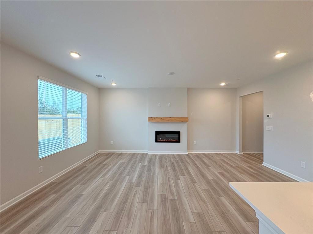 Modern living room with gas fireplace, hardwood floors, and large windows in Davidson Homes The Wake E, Cumming, Georgia