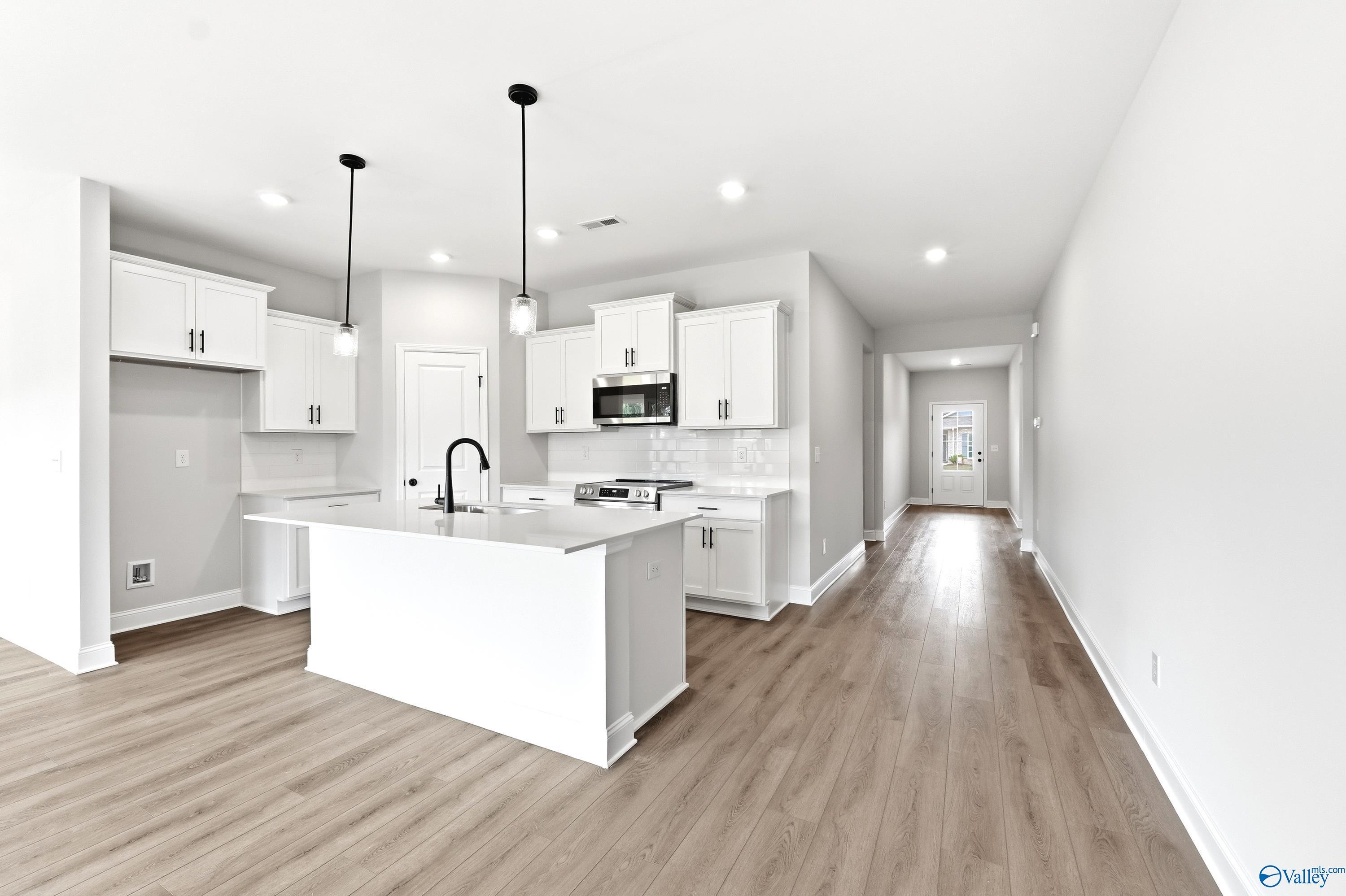 Modern white kitchen with island and pendant lighting in The Daphne C floor plan at Flint Meadows, New Market, Alabama.