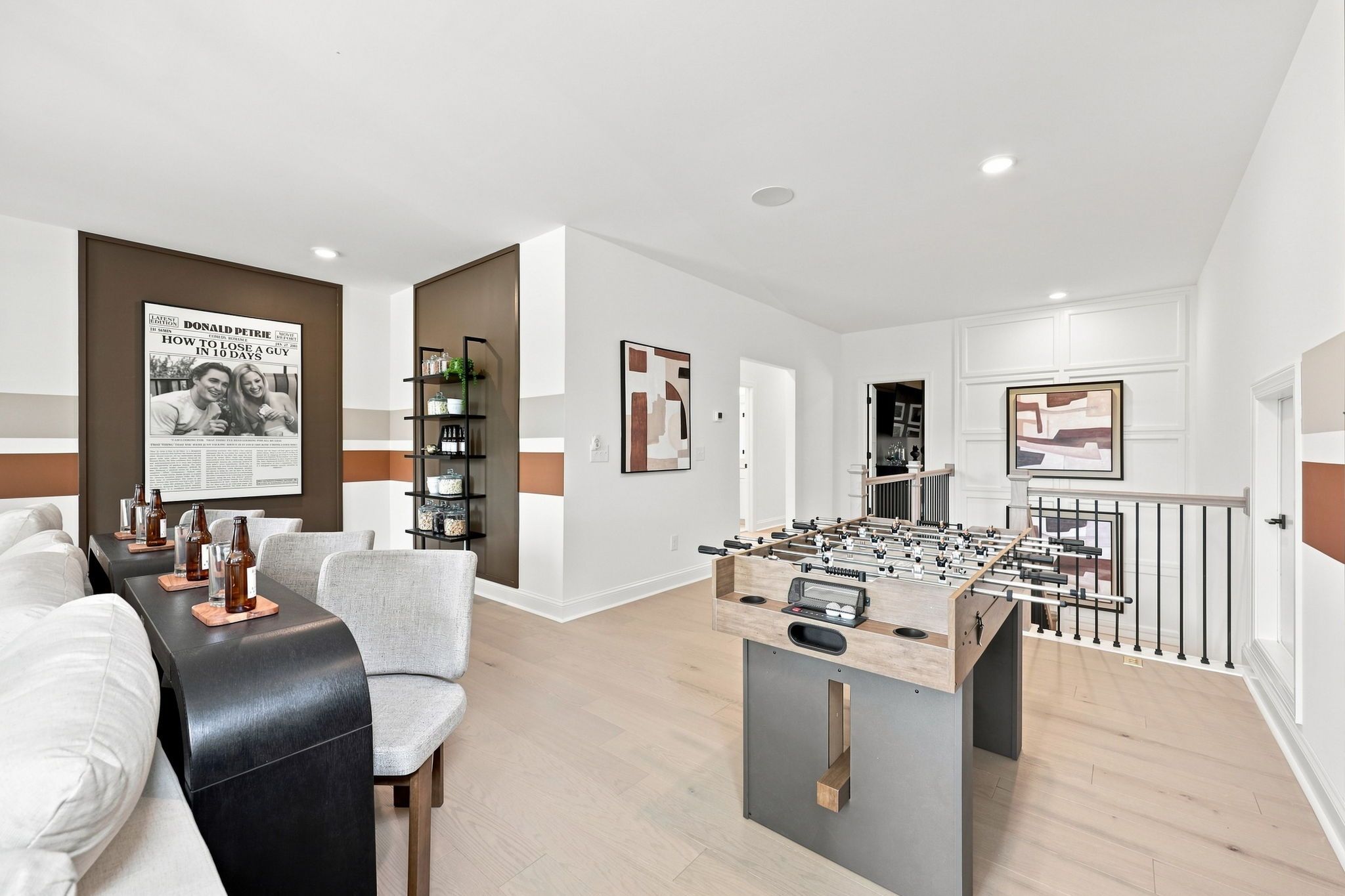 Spacious game room in The Barrington C featuring a foosball table, modern seating area, and stylish accent wall decor.