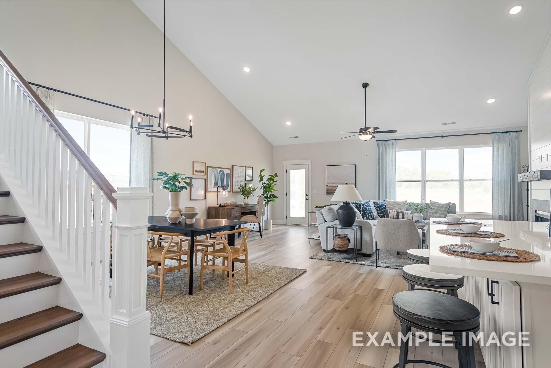 Open-concept living and dining space with wooden staircase and modern kitchen island in The Ridgeport home, Gallatin, TN