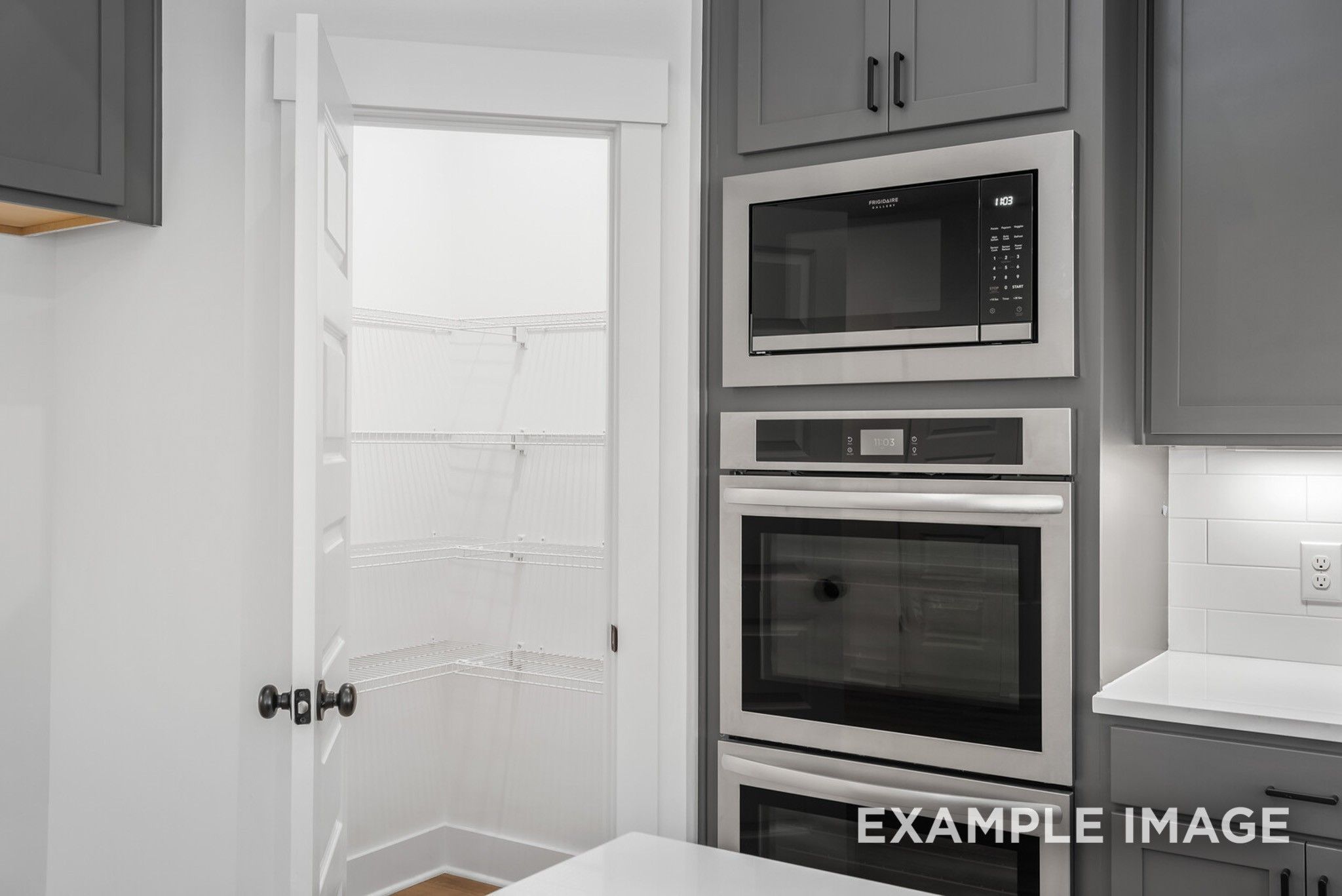Modern kitchen with open walk-in pantry, stainless microwave, double wall oven, and gray shaker cabinets in Davidson Homes Ridgeport C, Gallatin, TN
