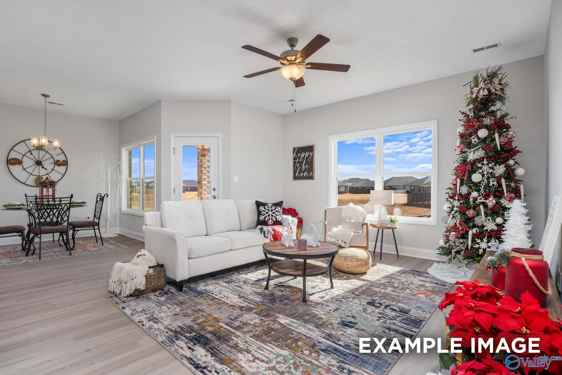 Cozy living room with festive Christmas tree, white sofa, ceiling fan, and large windows in 4-bedroom Davidson Homes The Daphne D, Meridianville, AL