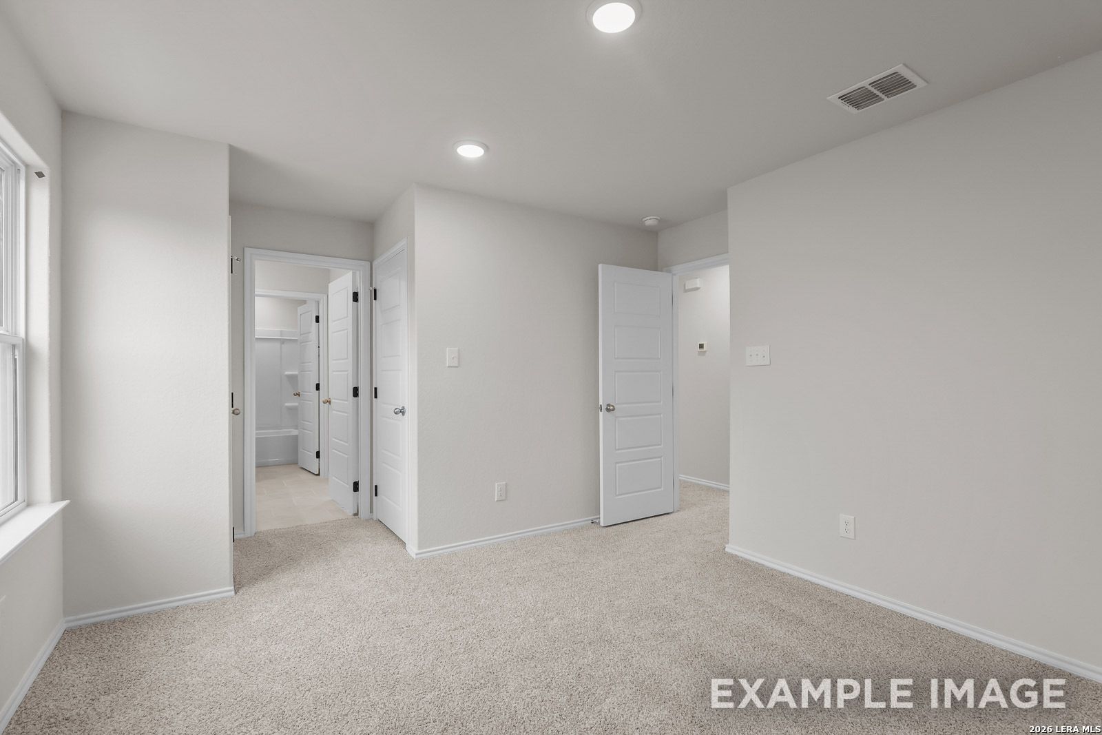 Spacious bedroom with carpeted flooring and adjacent en suite bathroom in The Sequoia C plan, Royal Crest, San Antonio.