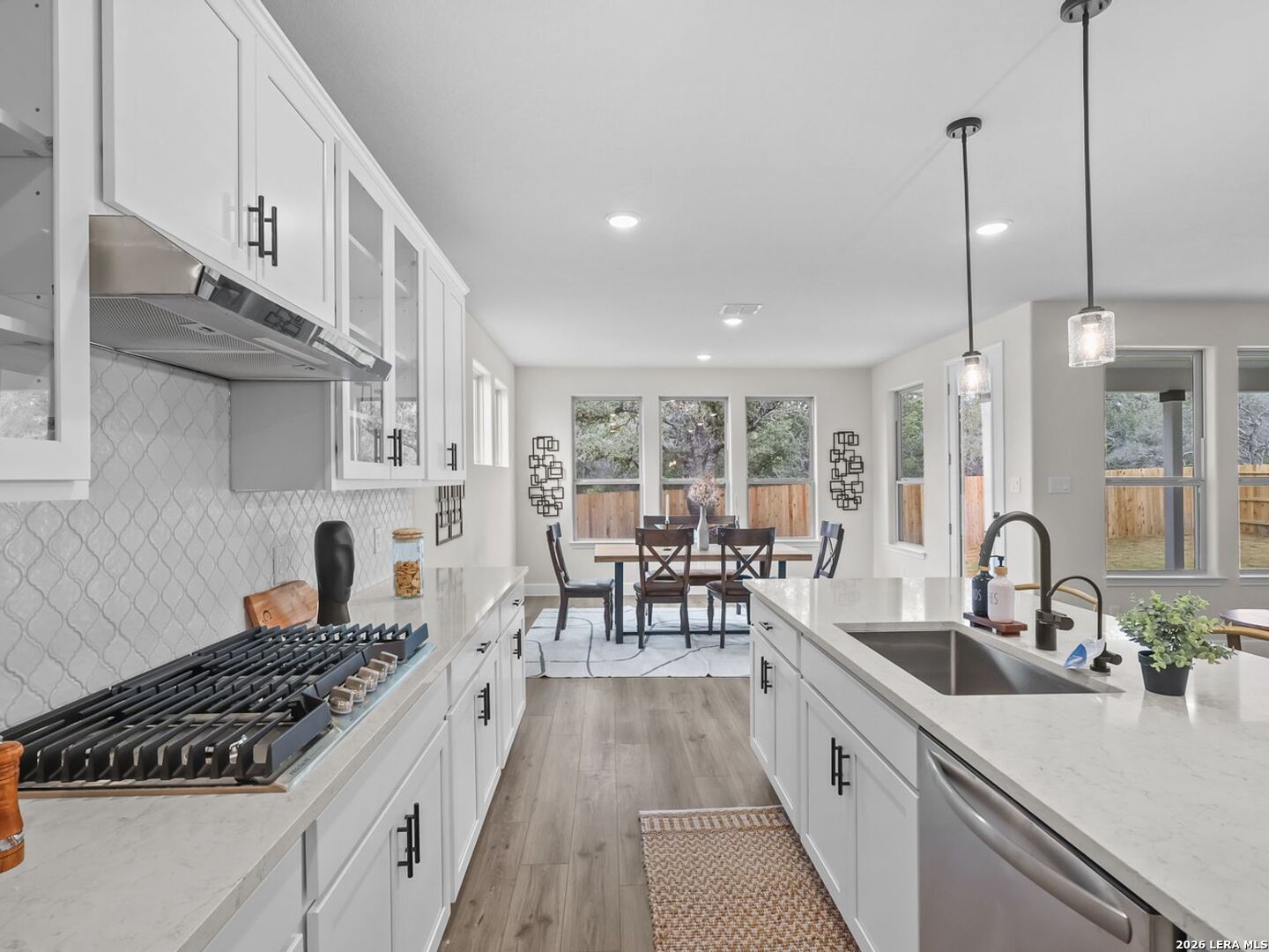 Modern kitchen with white cabinets, quartz countertops, and dining area in The Belmont H home, Potranco Oaks, Castroville.
