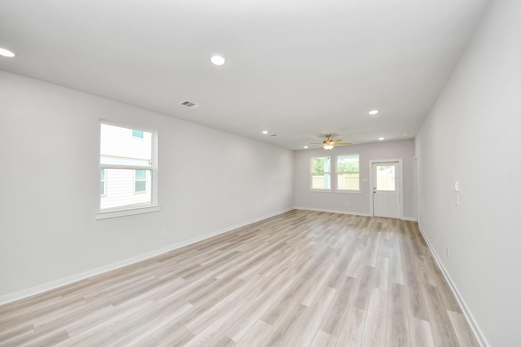 Spacious, open-concept living area with light wood flooring in The Sabine F floor plan at Liberty Estates, Cleveland, TX.