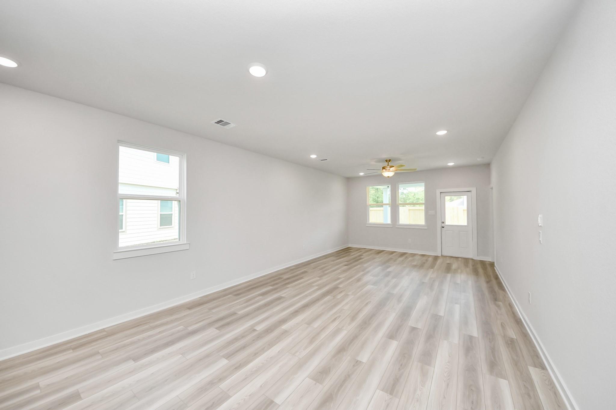 Spacious, open-concept living area with light wood flooring in The Sabine F floor plan at Liberty Estates, Cleveland, TX.
