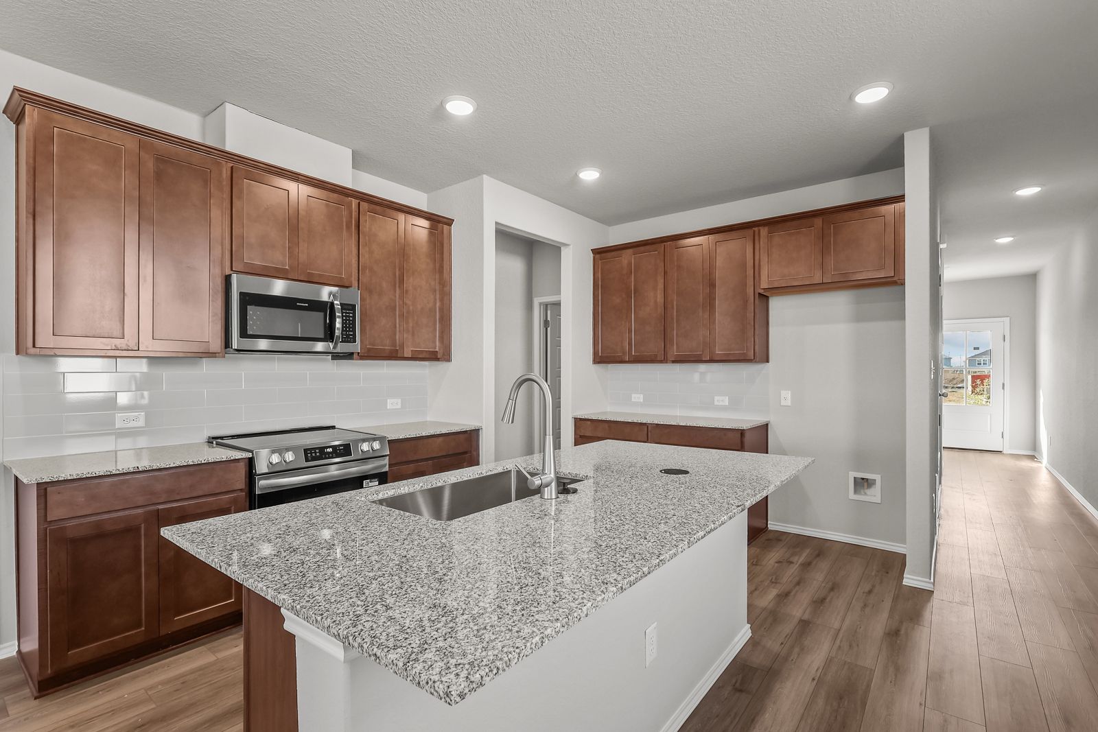 Modern kitchen in The Arroyo featuring granite countertops, wood cabinetry, and a spacious center island.