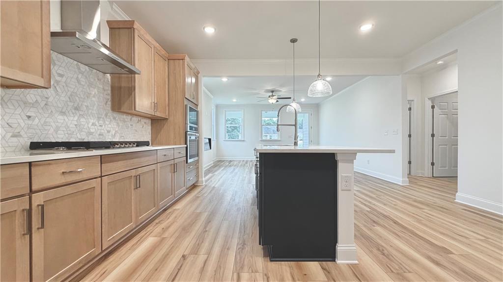 Modern kitchen with light wood cabinets, island, and tile backsplash in The Glenwood A home at Wehunt Meadows, Hoschton.