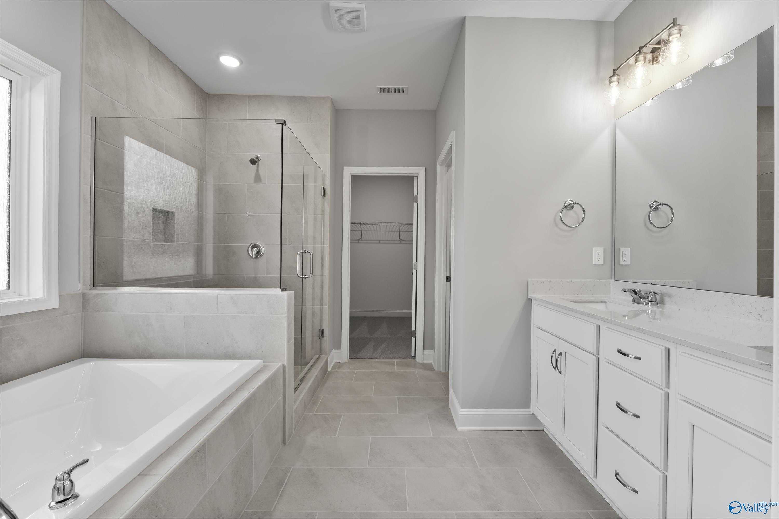 Modern master bathroom featuring frameless glass shower, soaking tub, and double vanity in Davidson Homes The Rockford, Harvest, Alabama
