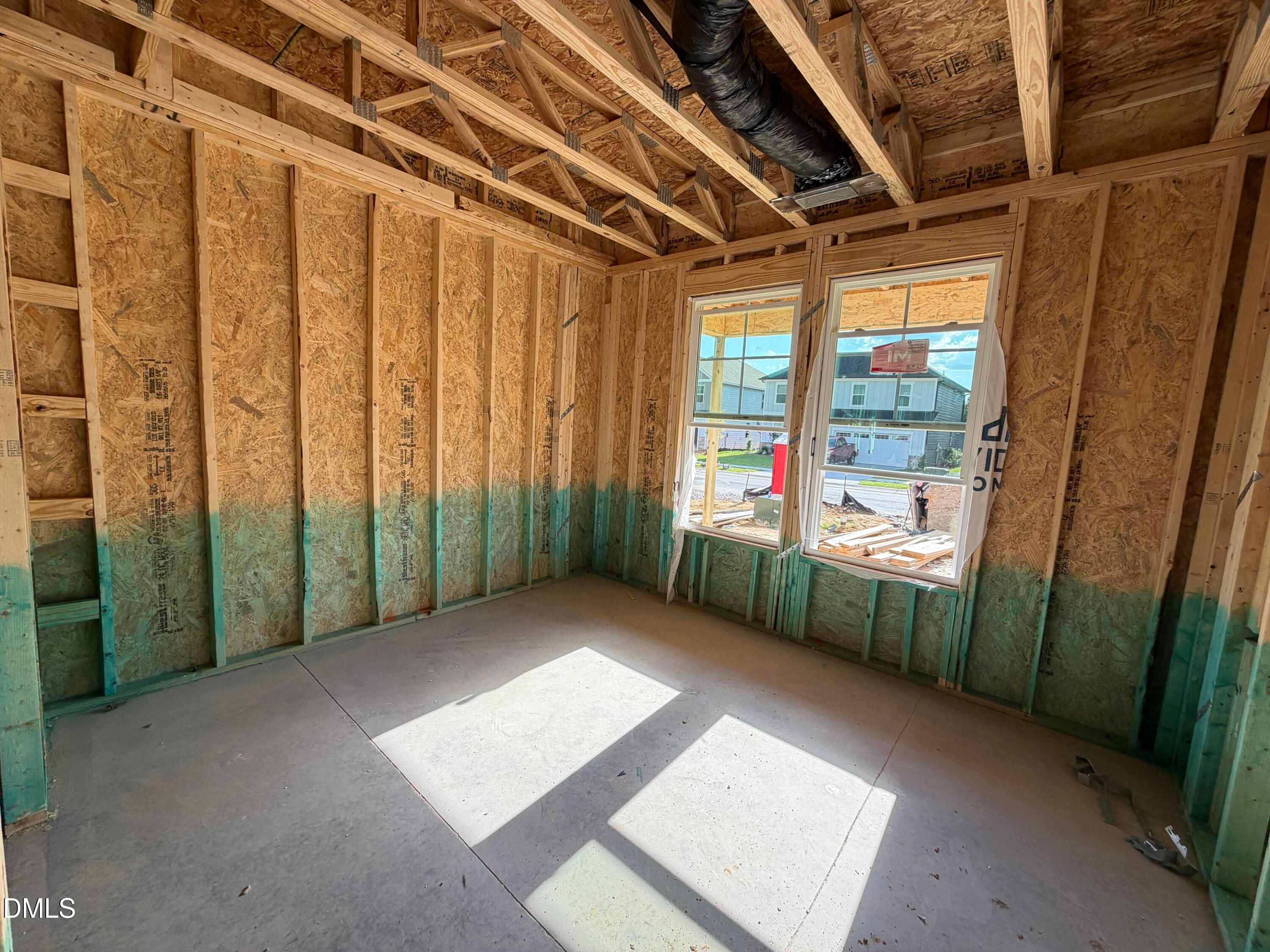 Framed room under construction with exposed wood studs and windows in The Beech floor plan home by Davidson Homes, Wendell Ridge, NC