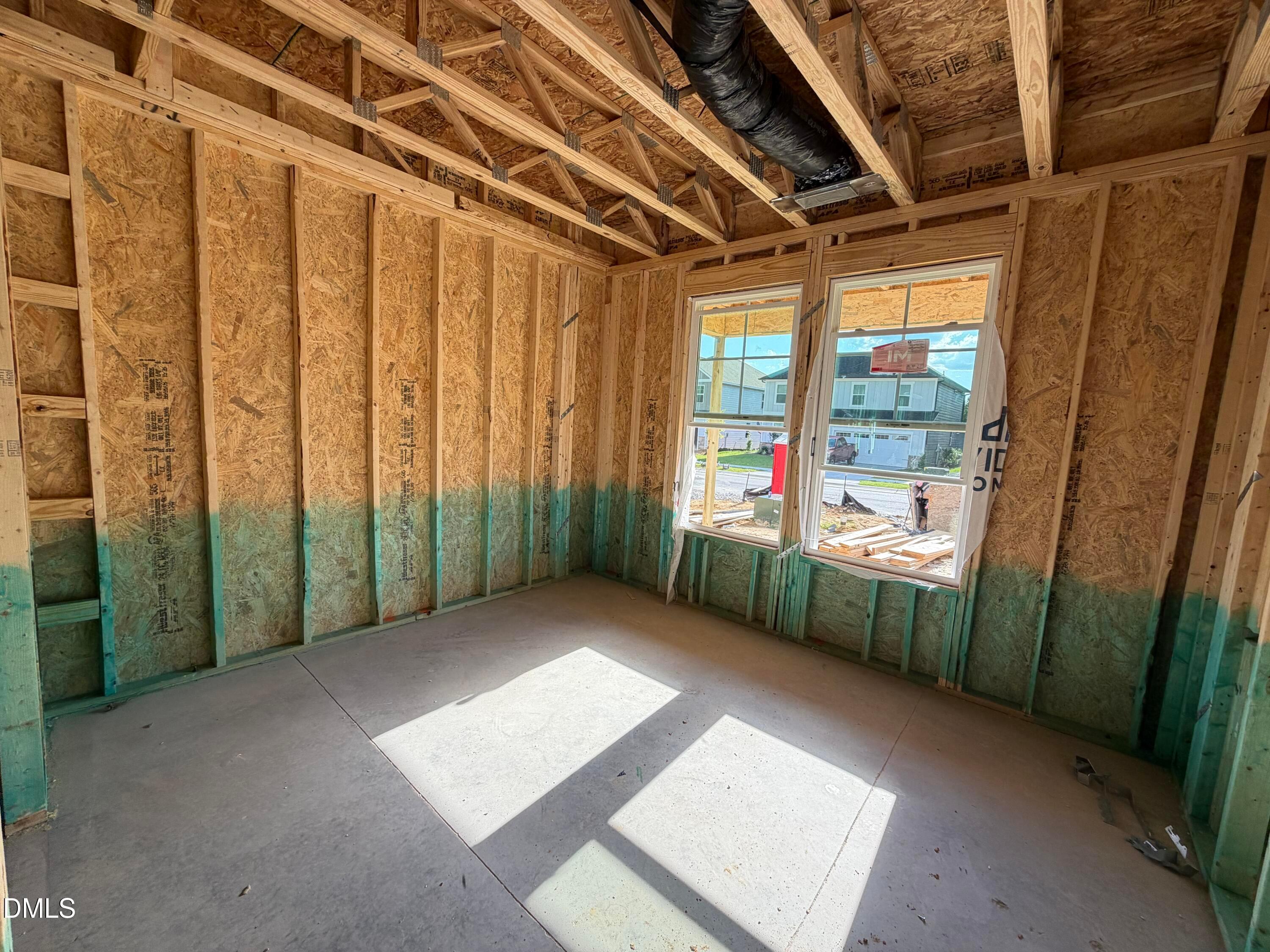Framed room under construction with exposed wood studs and windows in The Beech floor plan home by Davidson Homes, Wendell Ridge, NC