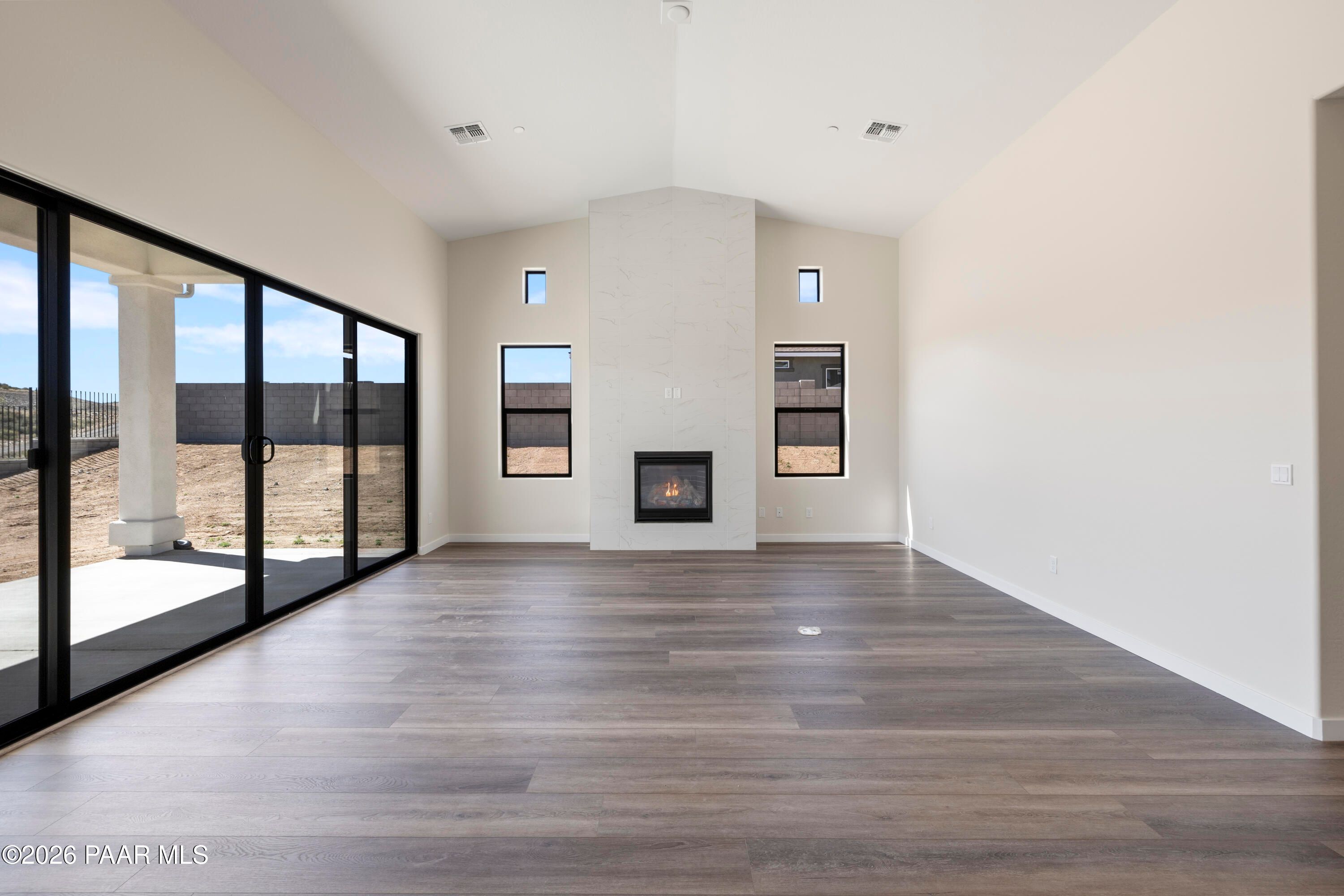 Spacious great room with vaulted ceiling, stone fireplace, and sliding glass doors to desert patio in Soleil E home, Prescott, AZ