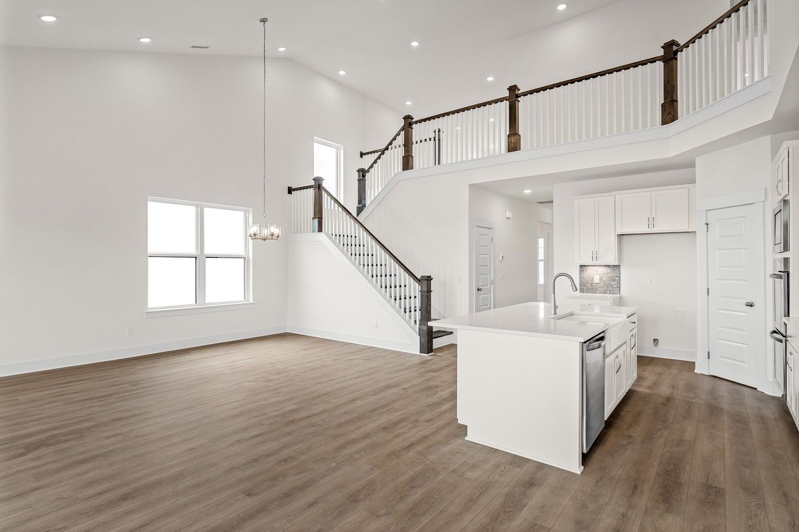 Spacious two-story interior with wooden staircase, white kitchen island, and hardwood floors in Davidson Homes Ridgeport D, Mt. Juliet