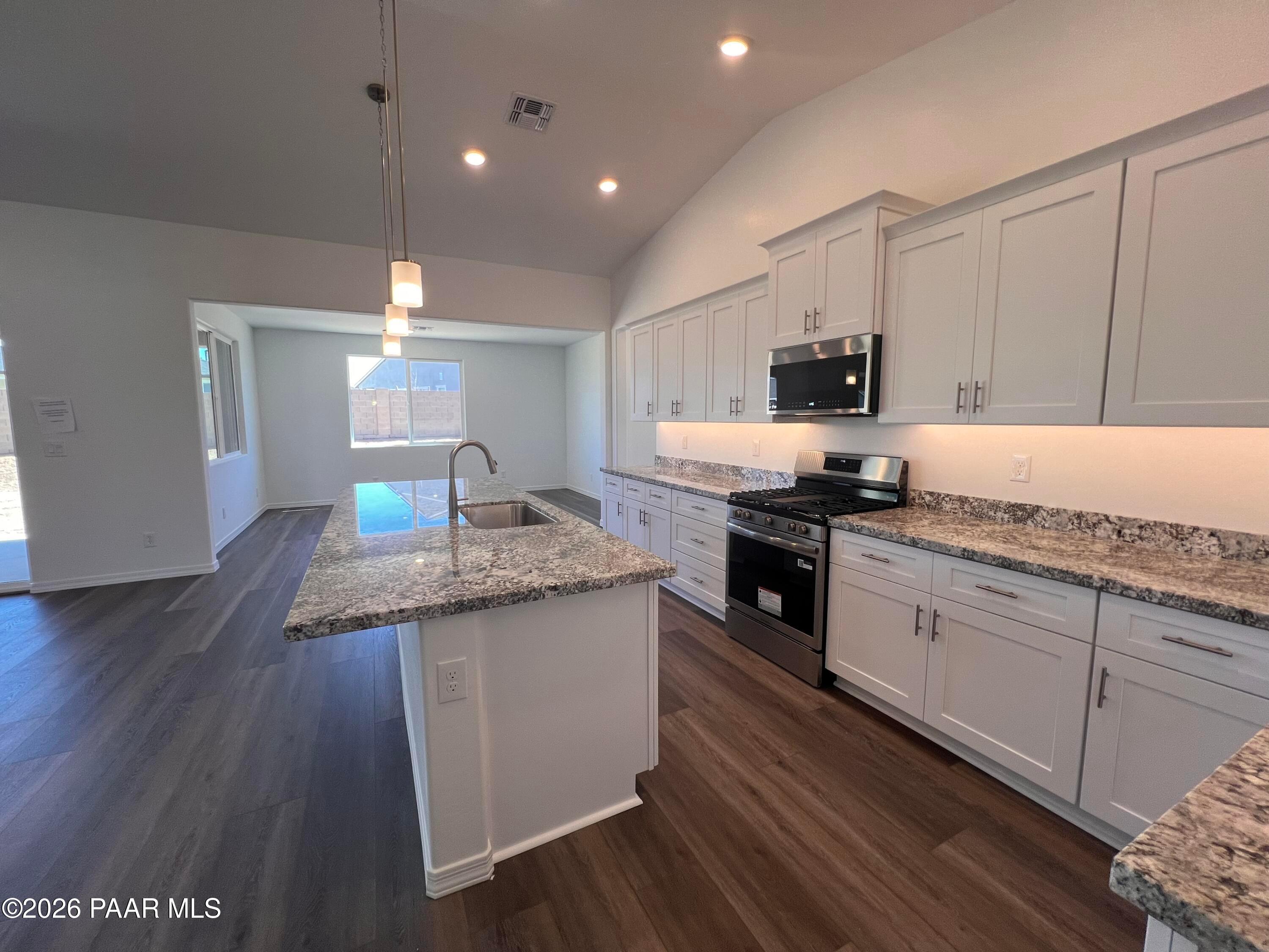Modern white kitchen with granite island sink, stainless steel range, and open layout in Davidson Homes Sunrise II A, Prescott AZ