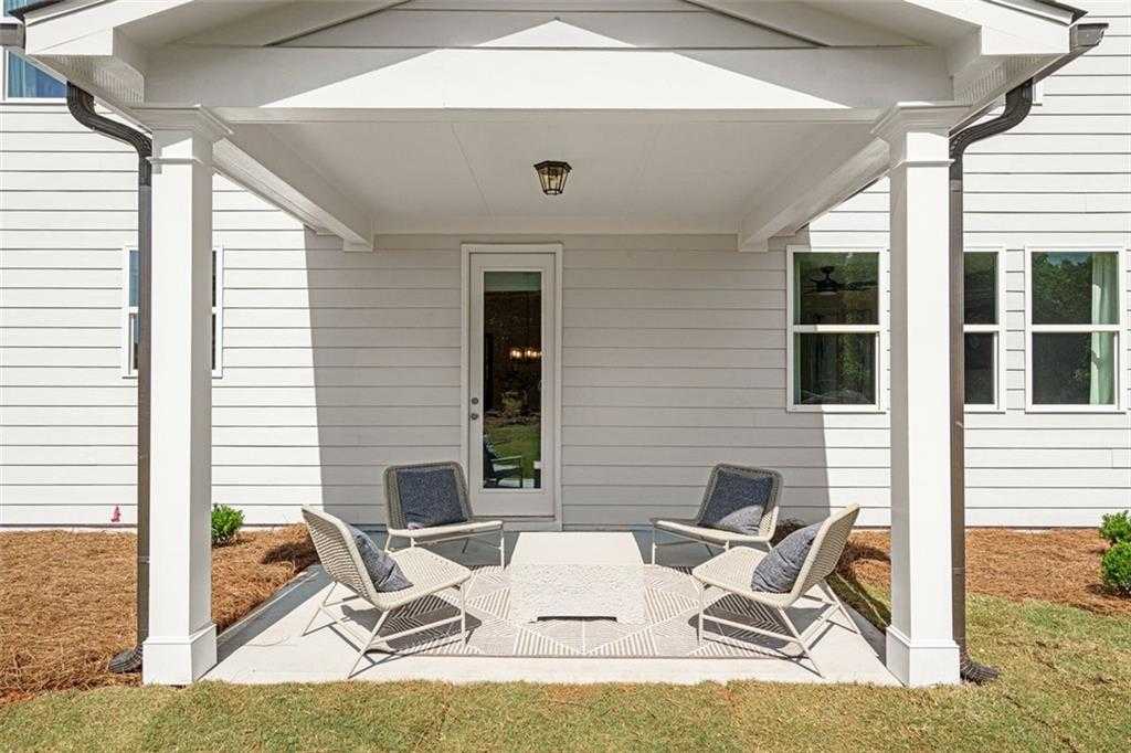 Covered back porch with gray patio chairs, coffee table, and French doors in Davidson Homes The Hickory C, Hoschton, Georgia