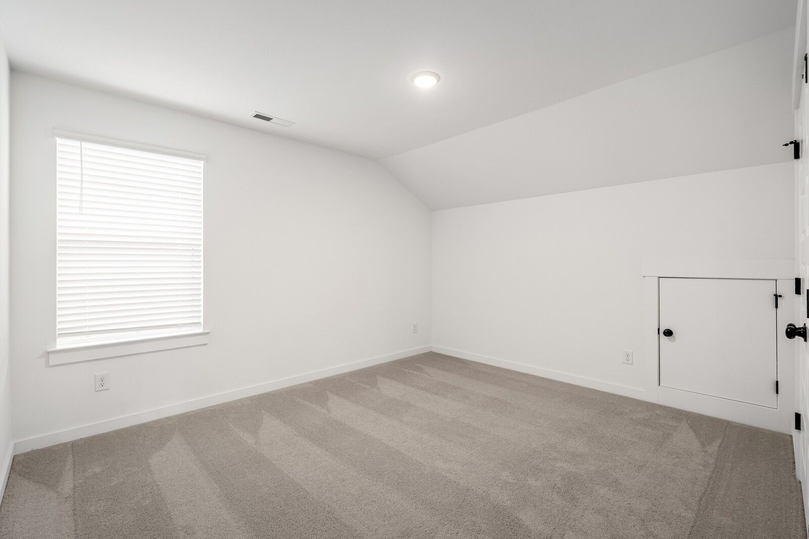Bright empty bedroom featuring vaulted ceiling, large window with blinds, beige carpet, and closet door in Davidson Homes The Ridgeport, Gallatin, TN
