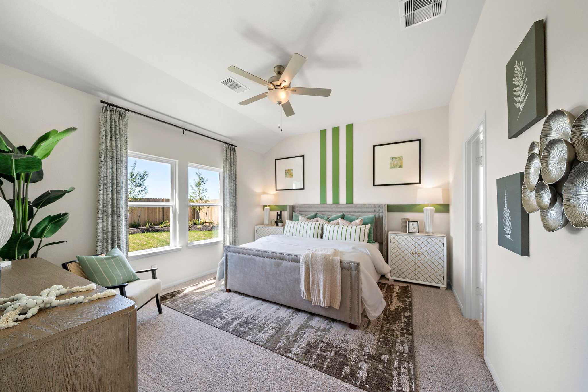 Spacious primary bedroom at River Ranch Meadows in Dayton Texas with king bed ceiling fan green accent wall and garden views