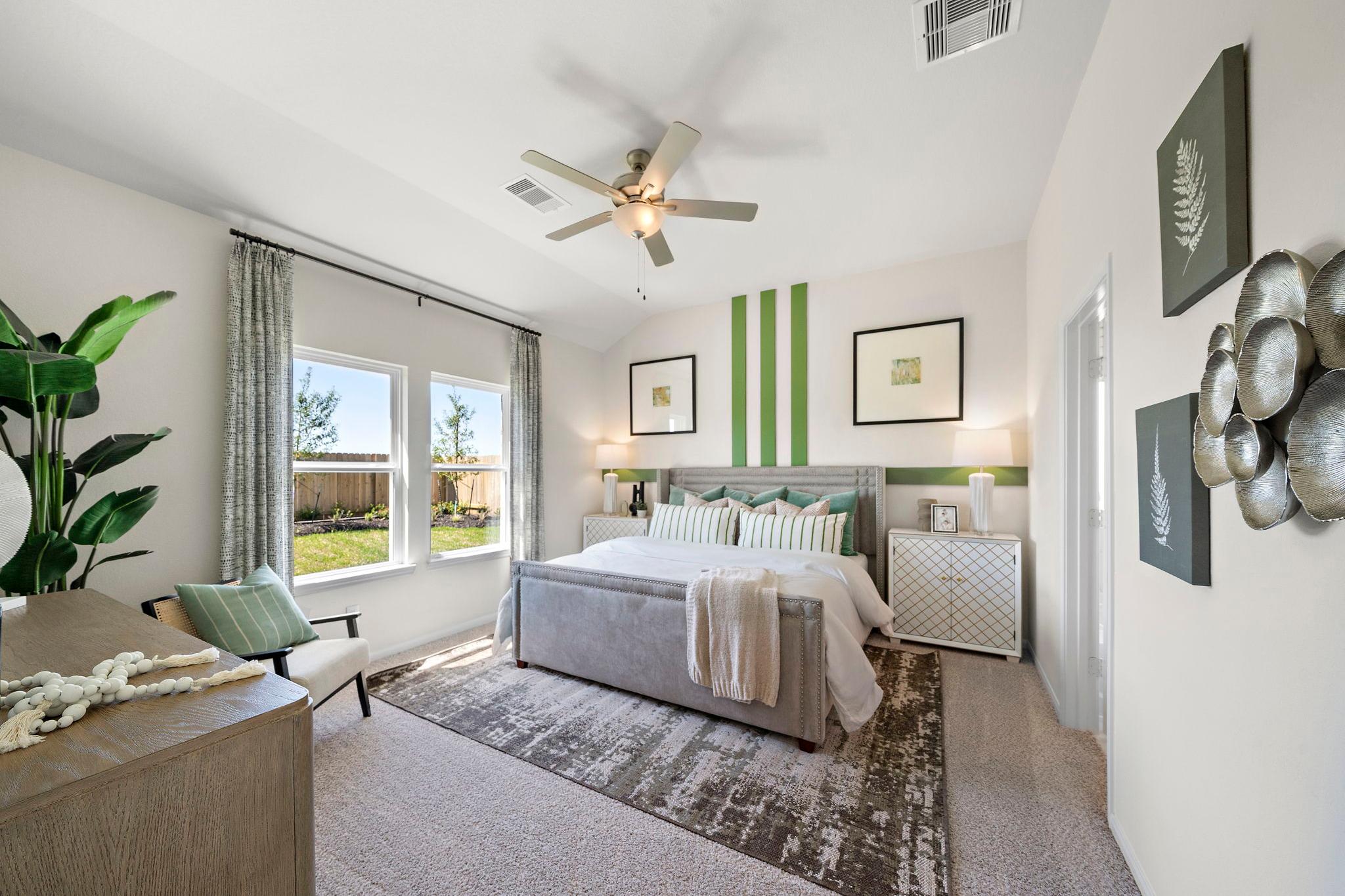 Spacious primary bedroom at River Ranch Meadows in Dayton Texas with king bed ceiling fan green accent wall and garden views