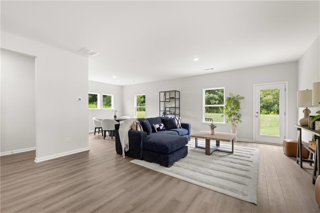 Open-concept living room with navy sectional and dining area in The Sinclair B floor plan at Cedar Farms, Winder, Georgia.