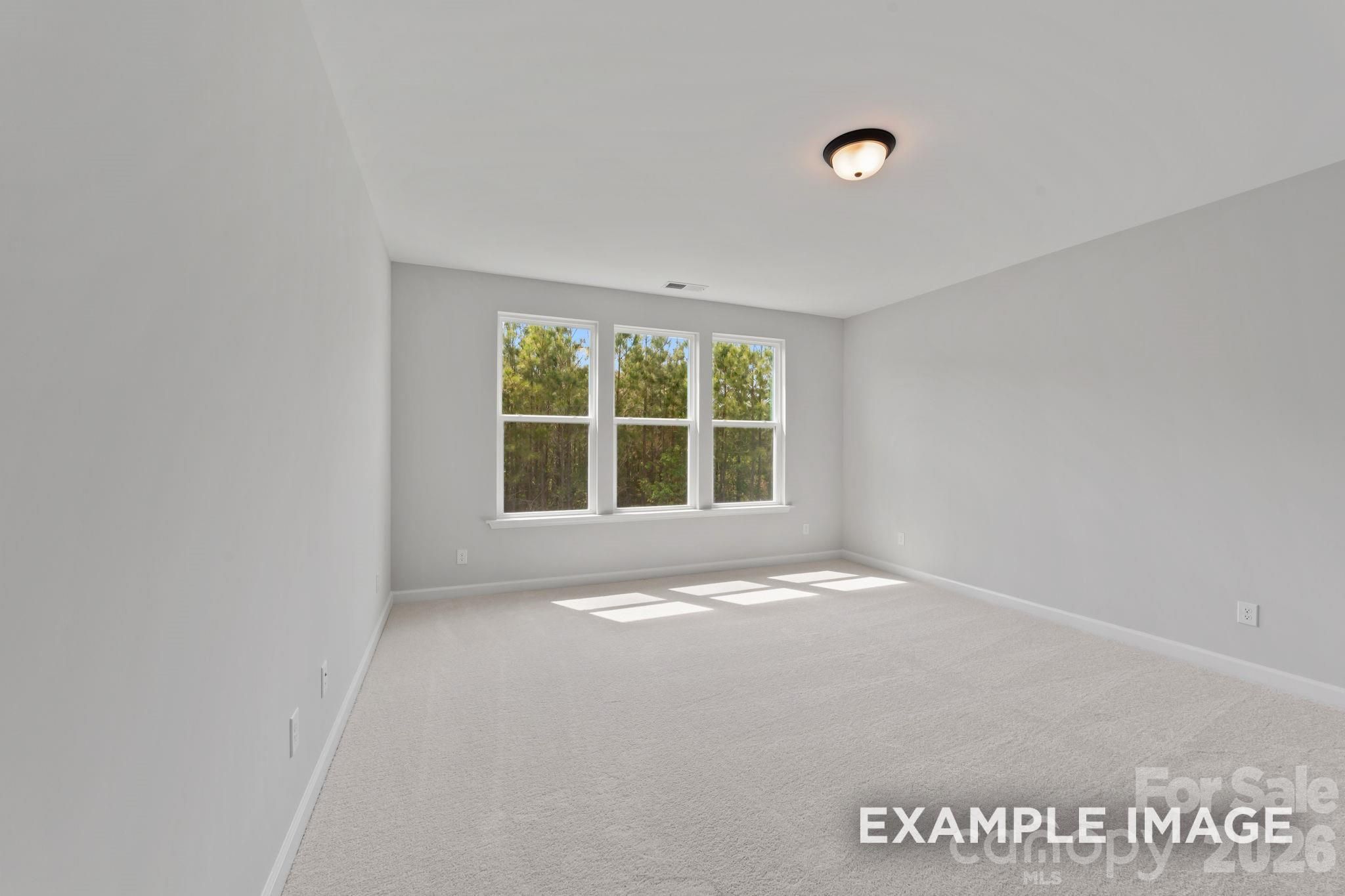 Bright, carpeted bedroom with large windows in The Magnolia B floor plan by Davidson Homes in Windgate, Mooresville, NC.