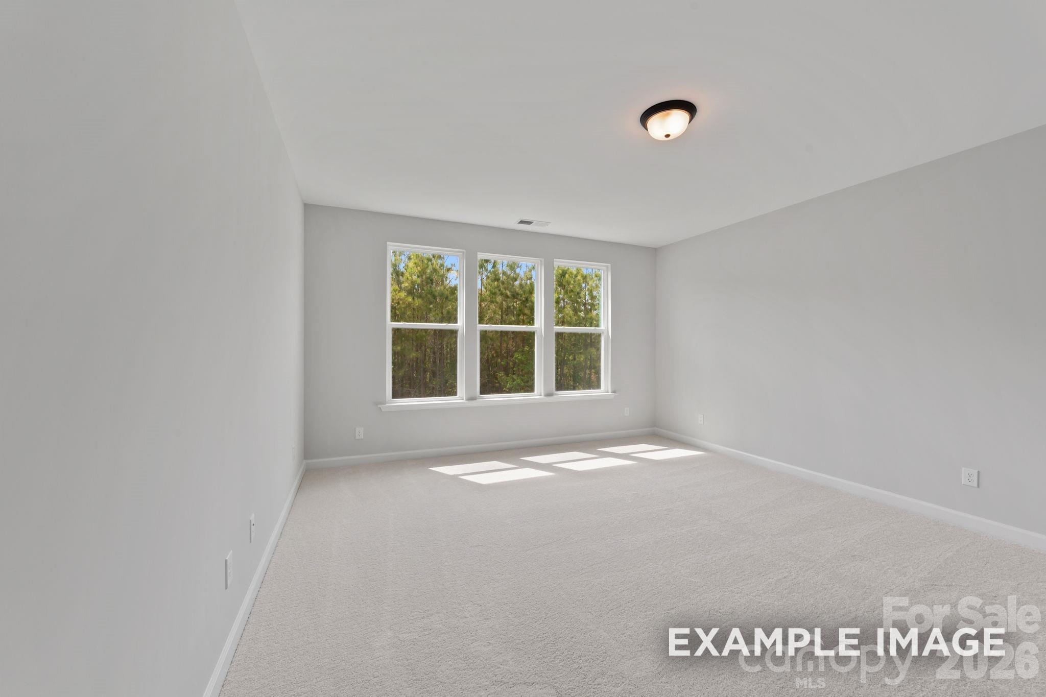 Bright, carpeted bedroom with large windows in The Magnolia B floor plan by Davidson Homes in Windgate, Mooresville, NC.