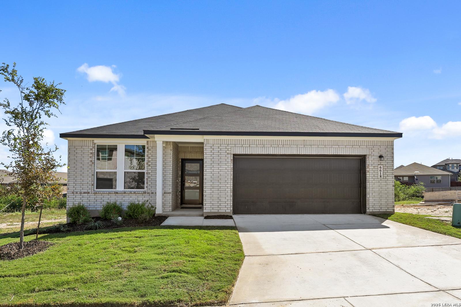 Single-story brick exterior with 2-car garage and landscaped yard at The Glenwood E by Davidson Homes in Comanche Ridge, San Antonio