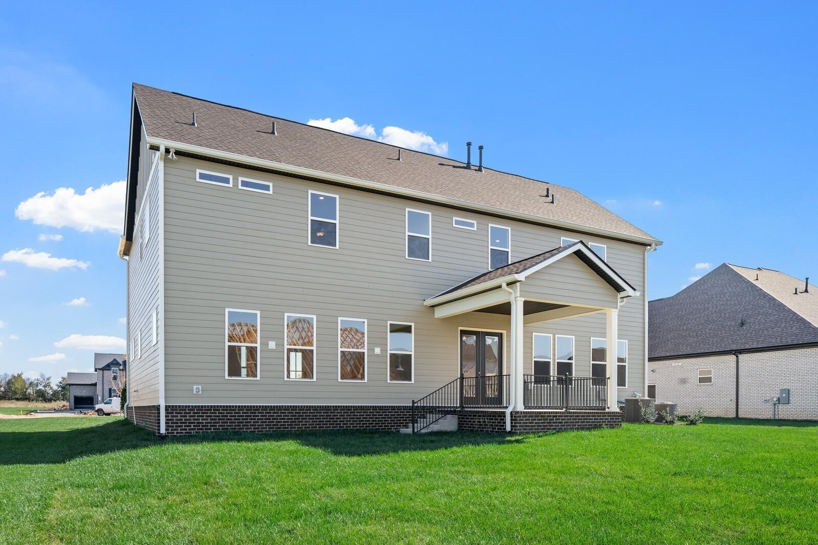 Modern 2-story beige home exterior with covered porch, large windows, and lush lawn in Shelton Square, Murfreesboro, TN