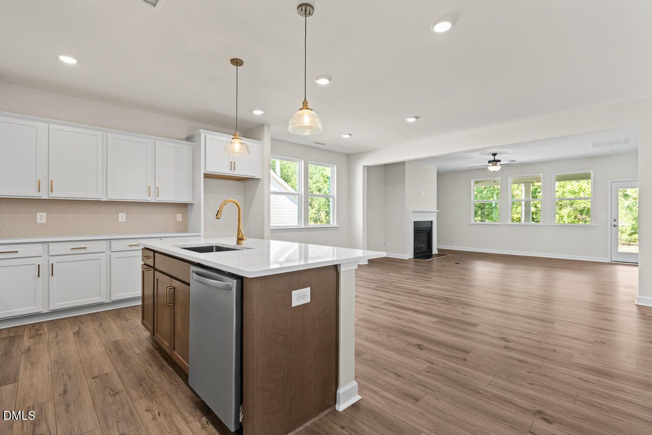 Open-concept kitchen with white cabinets, island, and hardwood floors in Davidson Homes Birch II C, Wake Forest, NC