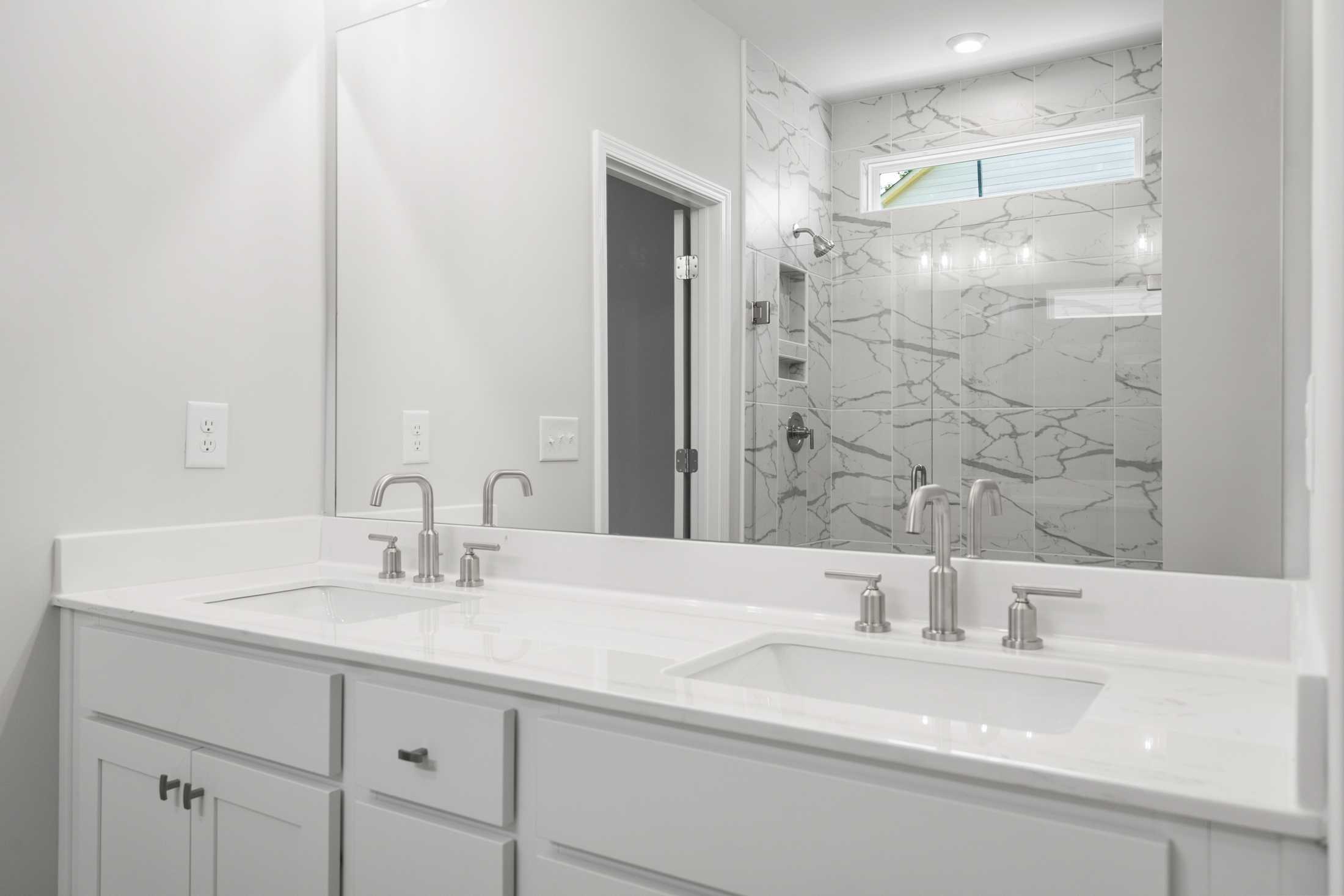 Spacious master bath in The Ash B featuring double vanity, white quartz counters, chrome faucets, and frameless glass shower