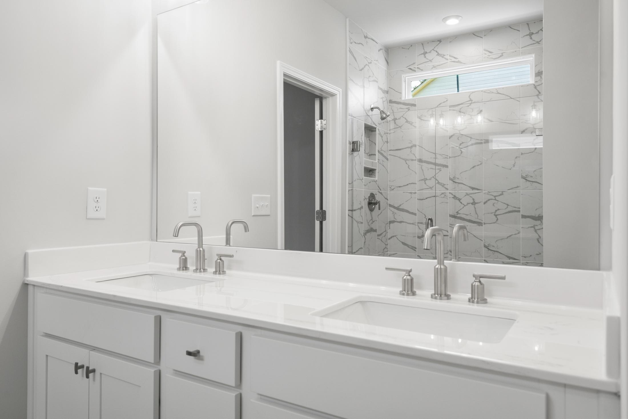 Spacious master bath in The Ash B featuring double vanity, white quartz counters, chrome faucets, and frameless glass shower