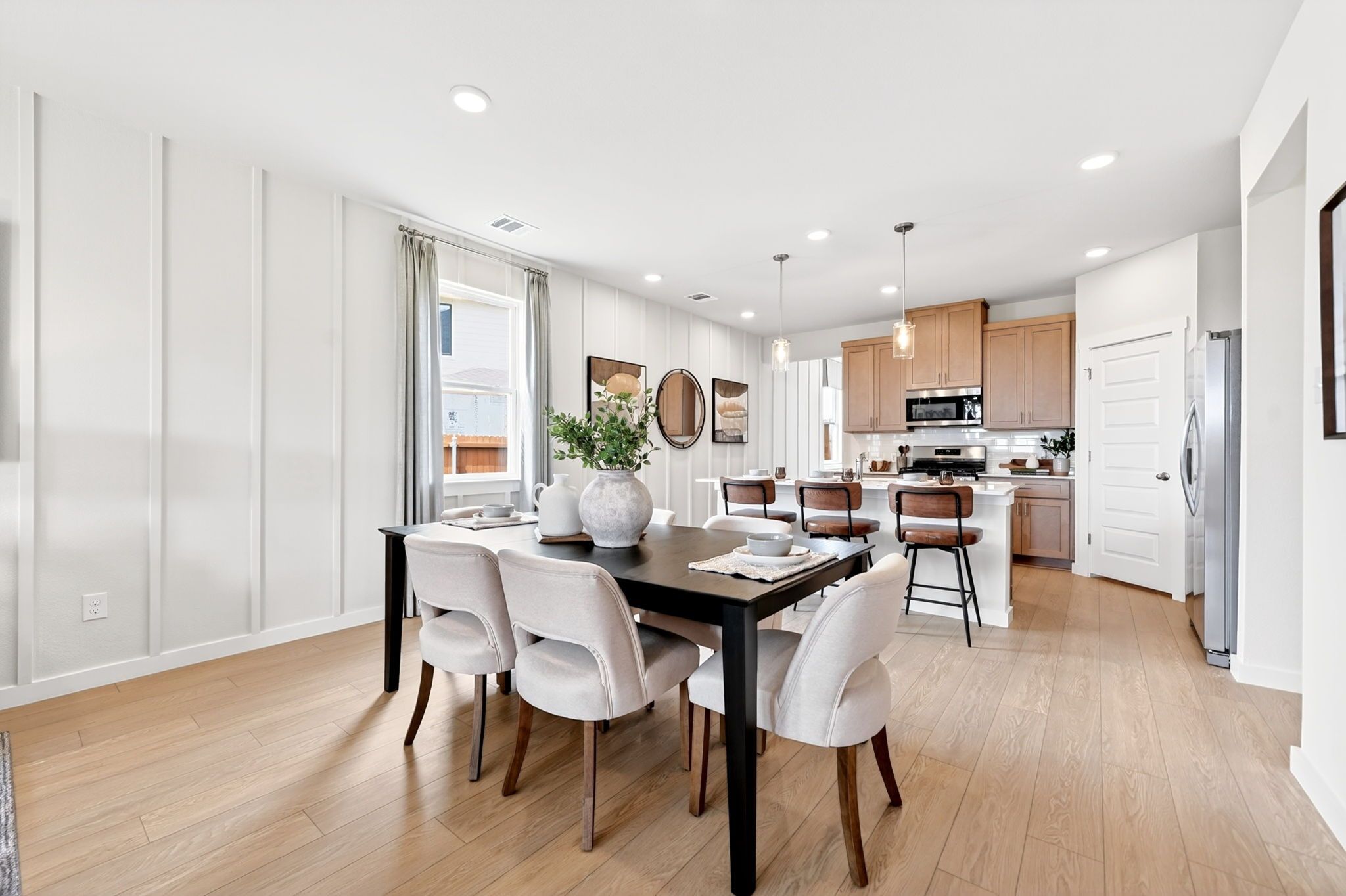 Open-concept dining and kitchen in Heartland Texas Davidson Homes with white shiplap walls, oak floors, black table, wood cabinets
