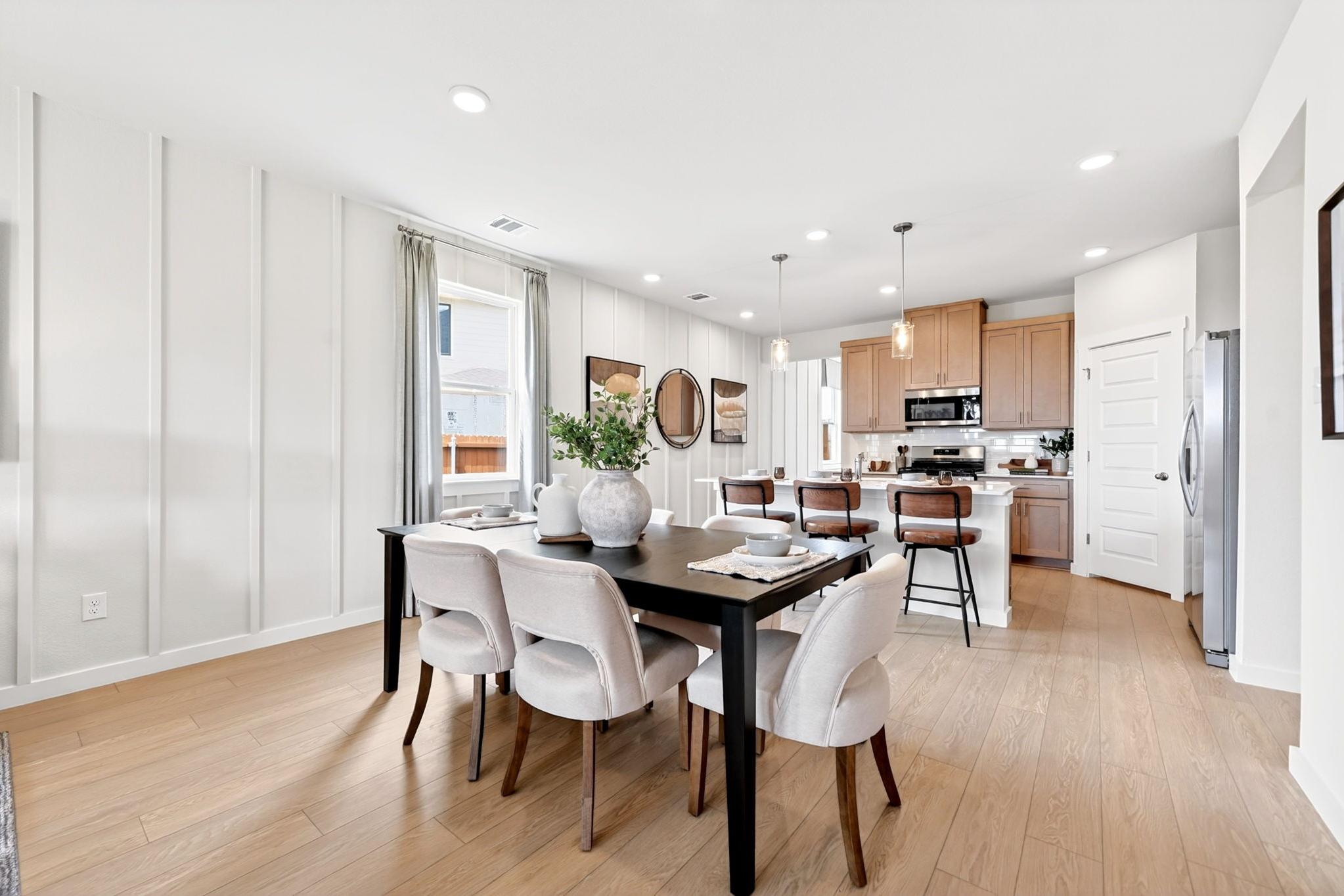 Open-concept dining and kitchen in Heartland Texas Davidson Homes with white shiplap walls, oak floors, black table, wood cabinets
