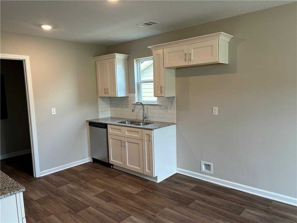 Bright kitchen with white shaker cabinets, subway tile backsplash, stainless sink, and wood flooring in The Washington home, Phenix City, AL