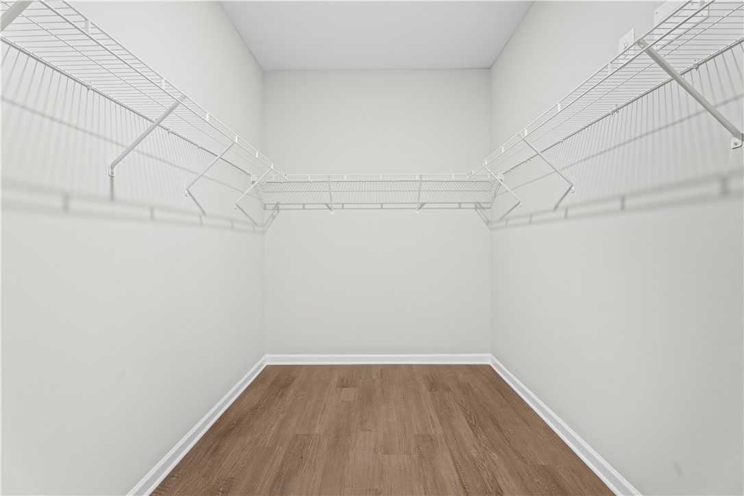 Spacious walk-in closet with white wire shelving and hardwood floors in Evermore Homes The Orion, Silver Oak, Cusseta, Alabama