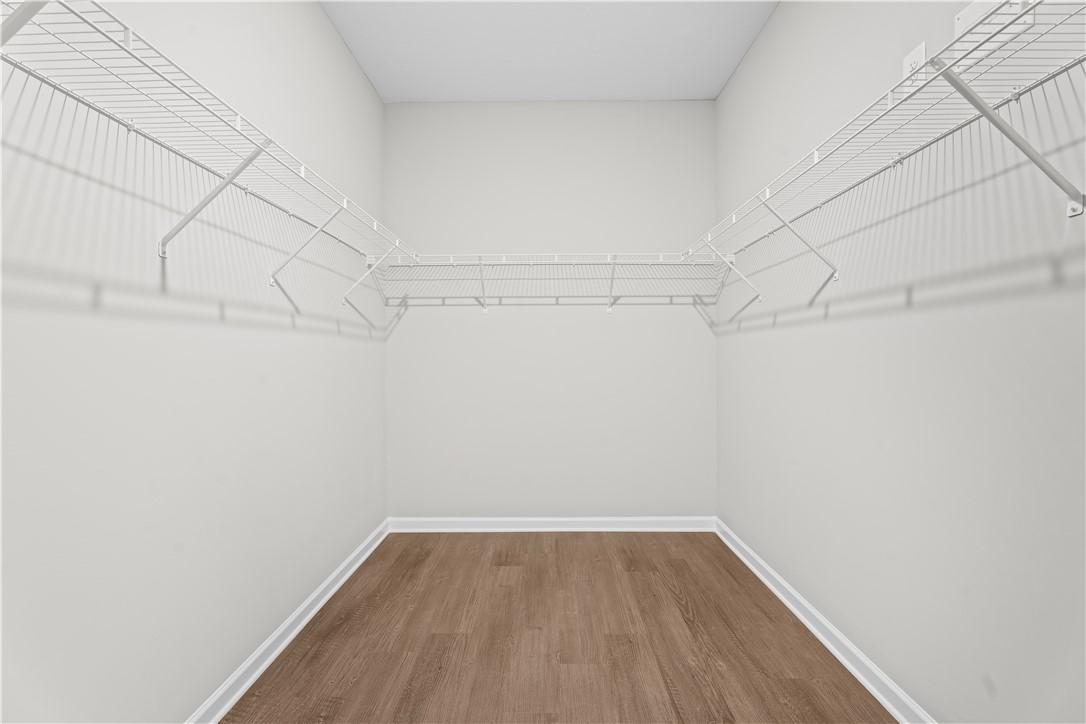 Spacious walk-in closet with wire shelving, hanging rods, and hardwood floors in Evermore Homes The Orion, Silver Oak, Cusseta, Alabama