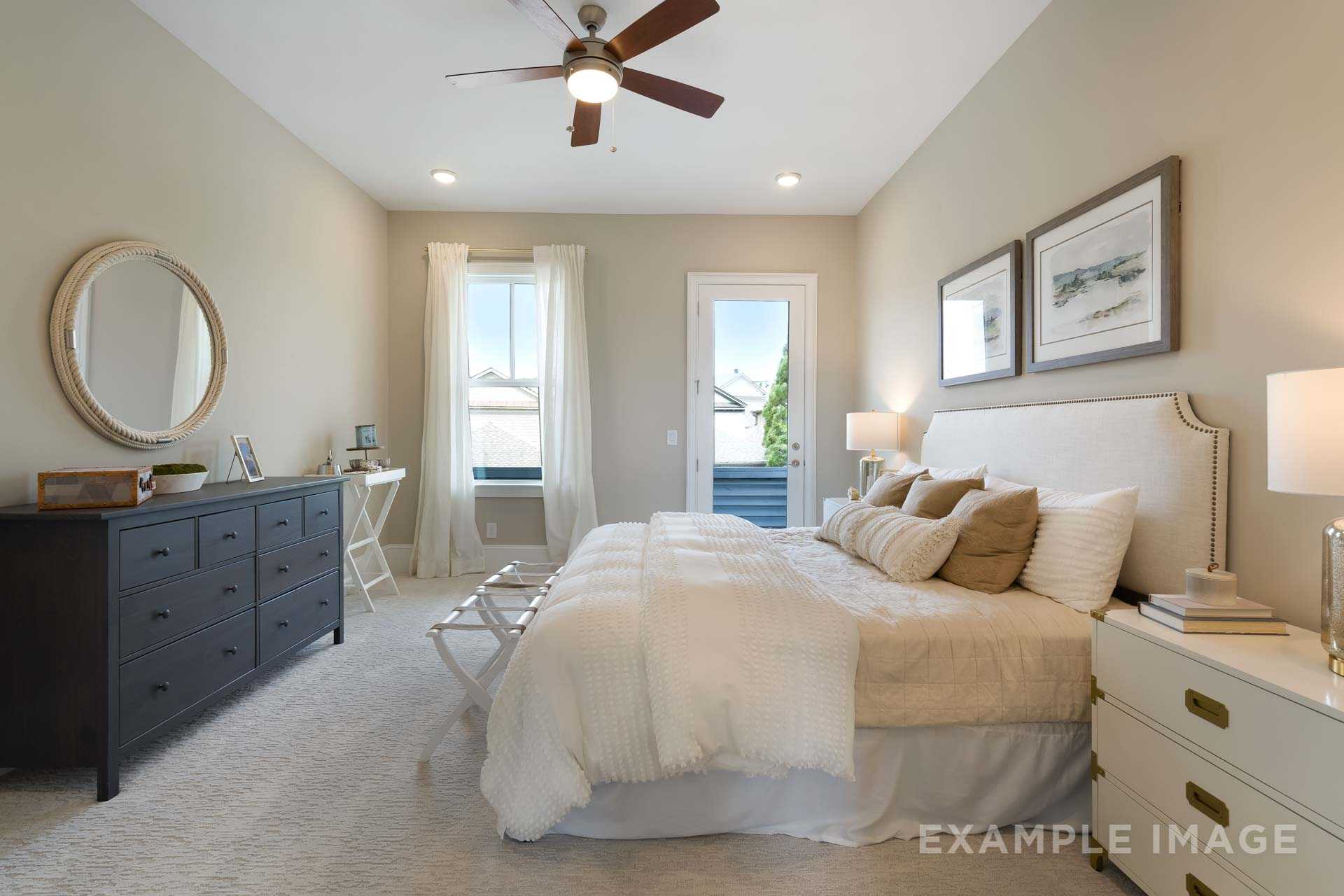 Spacious master bedroom in The Seaside home: king bed with beige pillows, French doors to balcony, ceiling fan, neutral tones