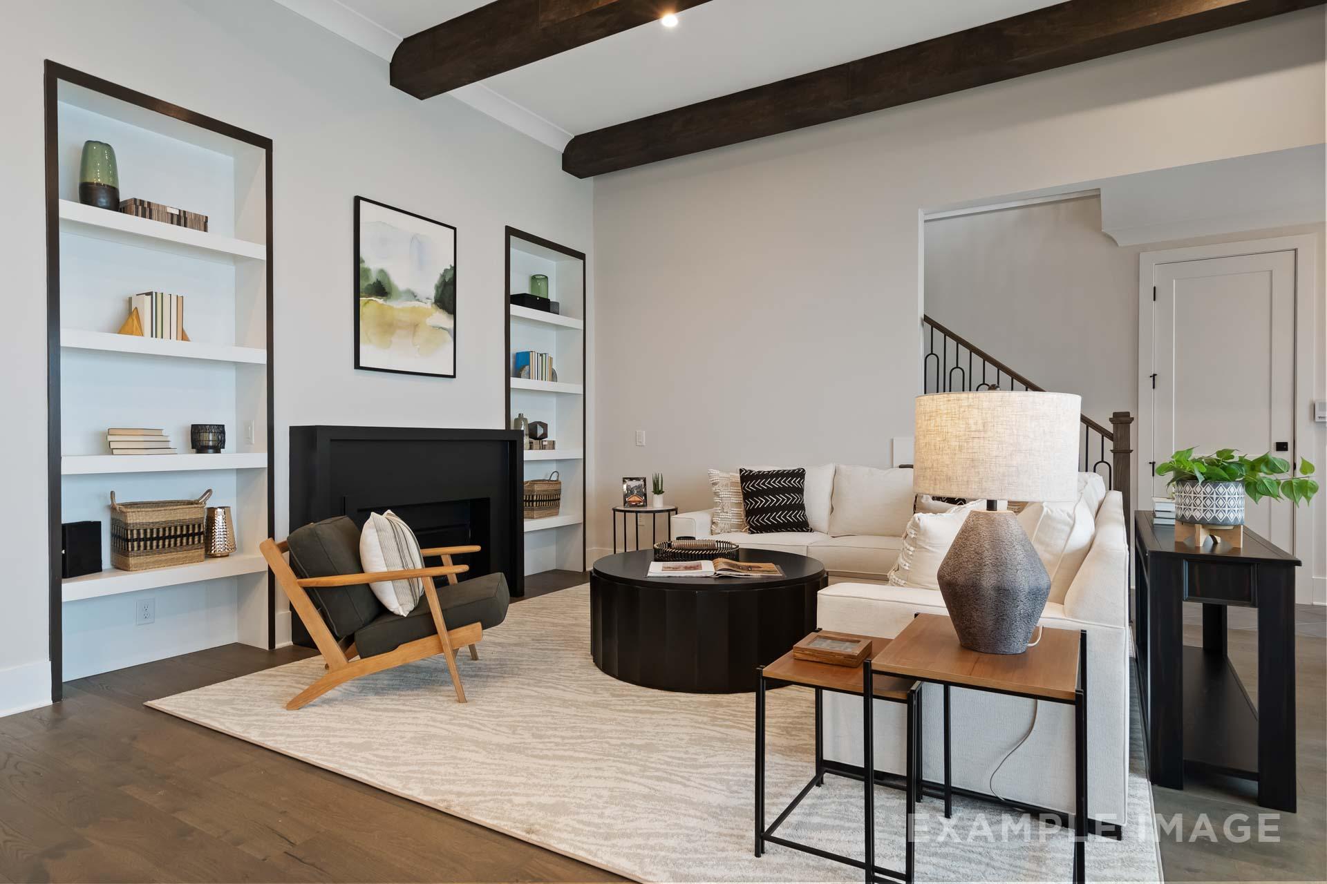 Spacious living room at Manor Estates in Marietta GA featuring exposed wood beams, built-in bookshelves, white sofa, stone fireplace, and hardwood floors