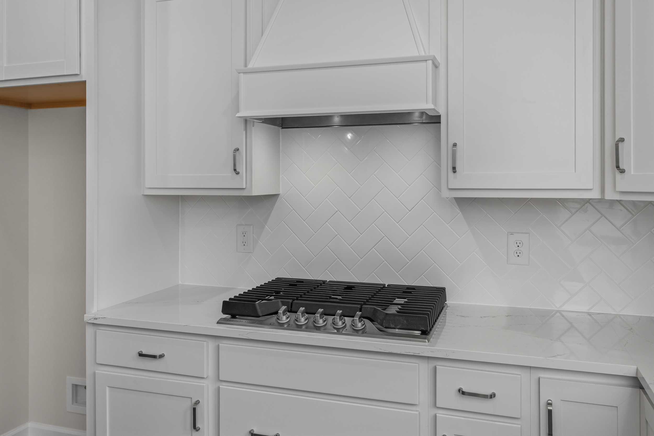 Spacious kitchen in The Aspen Davidson Homes featuring white shaker cabinets, subway tile backsplash, and gas range stove