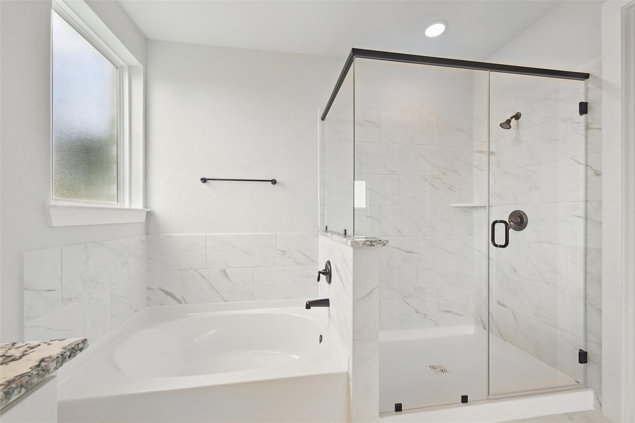 Elegant master bathroom with frameless glass shower, freestanding tub, and white subway tiles in Davidson Homes Victoria C, Lago Mar