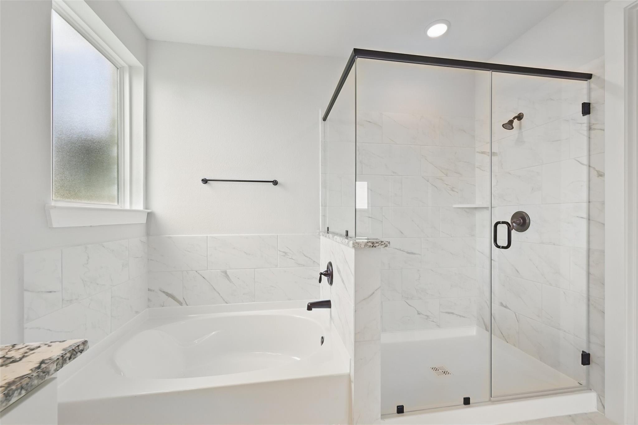 Elegant master bathroom with frameless glass shower, freestanding tub, and white subway tiles in Davidson Homes Victoria C, Lago Mar