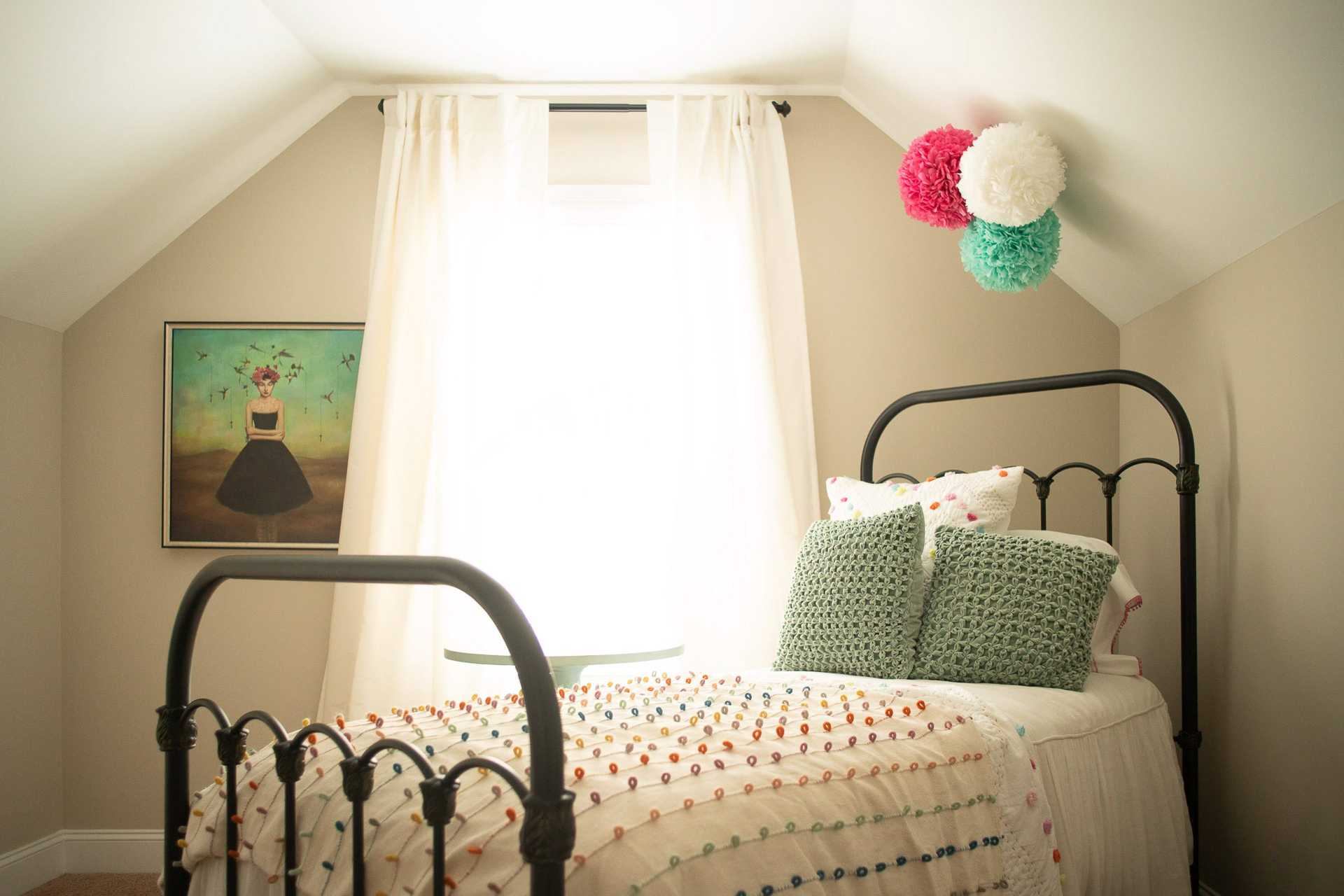 Cozy attic bedroom in Summer Pointe Madison Alabama with black metal twin bed, colorful quilt, green pillows, and Frida-inspired wall art
