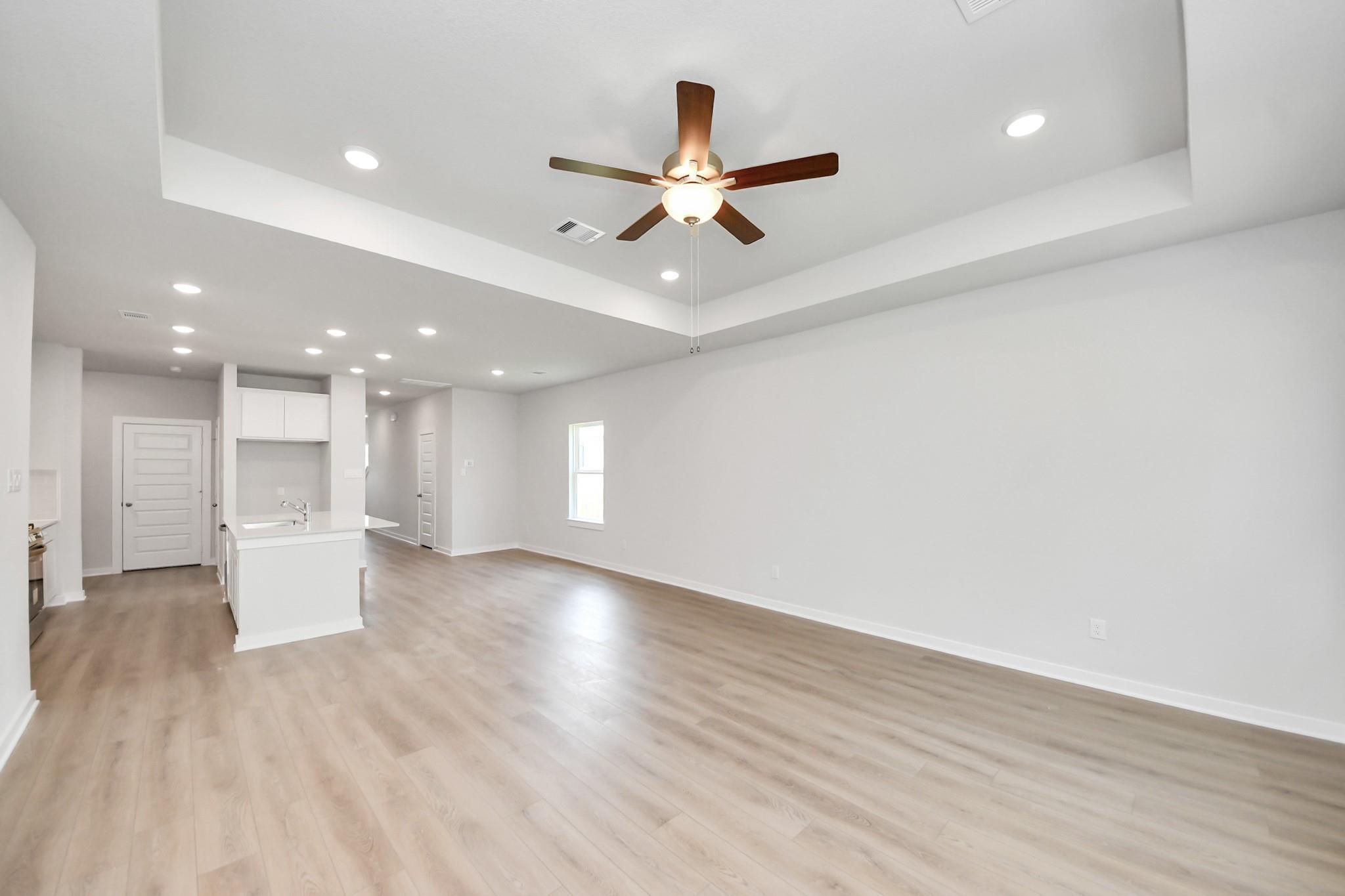 Bright, open-concept living area with tray ceiling in The Blanco E floor plan at Caney Creek Place, Conroe, Texas.