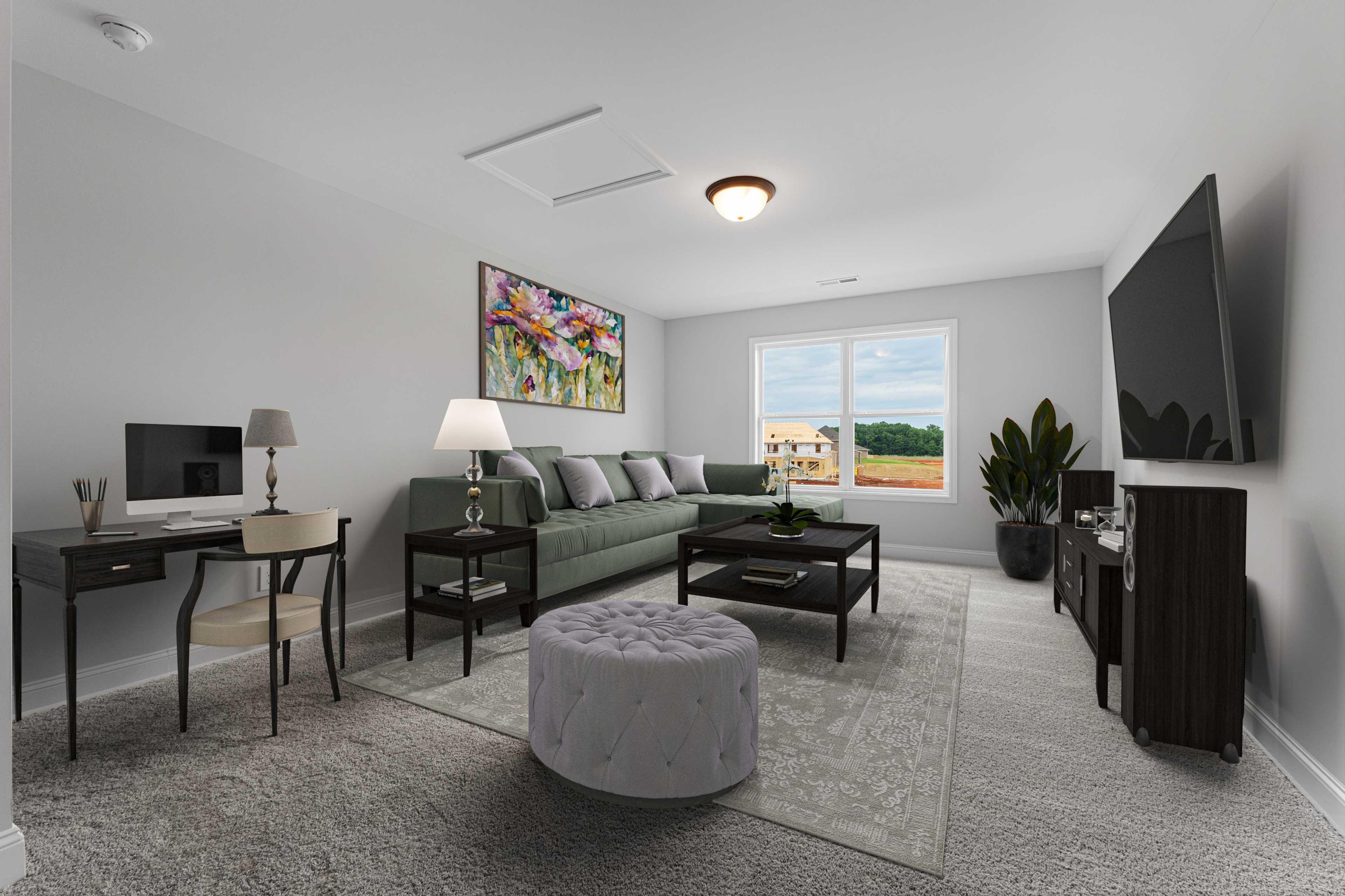 Modern living room interior at The Villas at Barnett's Crossing in Madison AL with green sectional sofa, mounted TV, desk, and large window view
