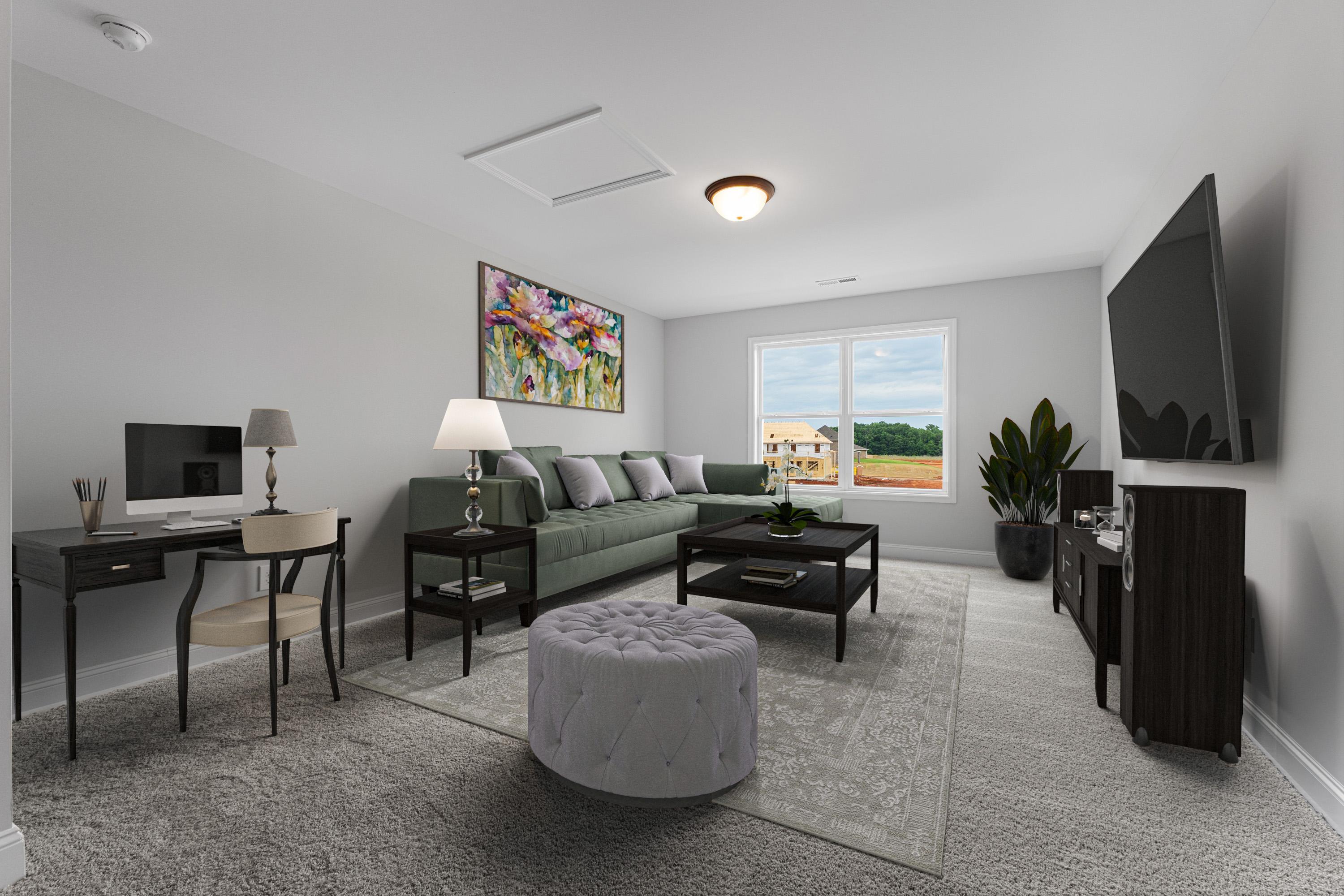 Modern living room interior at The Villas at Barnett's Crossing in Madison AL with green sectional sofa, mounted TV, desk, and large window view