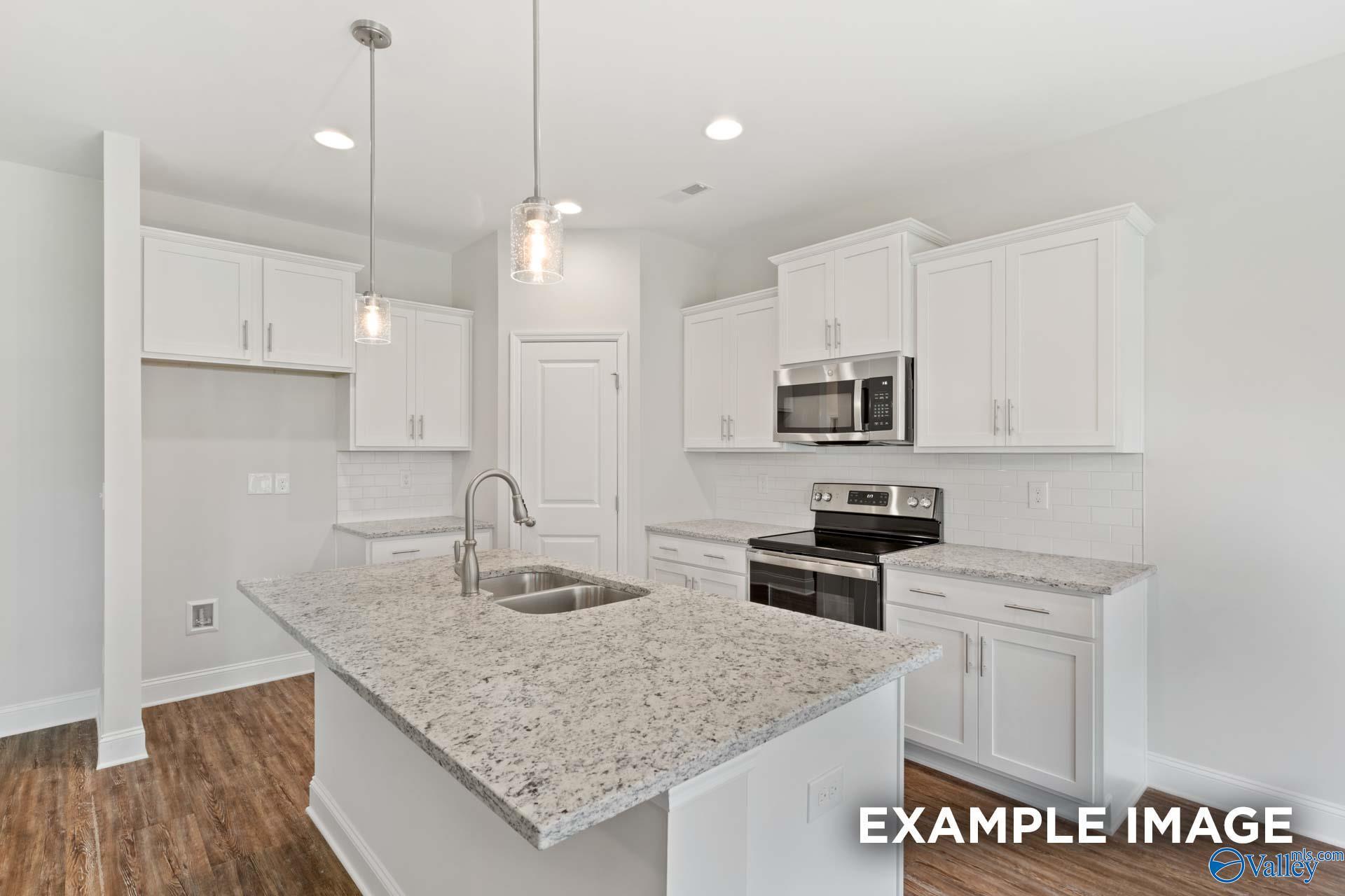 Bright modern kitchen with white shaker cabinets, granite island, stainless steel appliances in The Asheville C, Meridianville AL