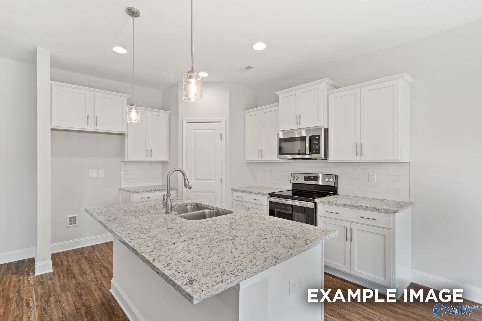 Modern white kitchen with granite island, stainless appliances, pendant lights in The Asheville C, Davidson Homes, Meridianville, AL