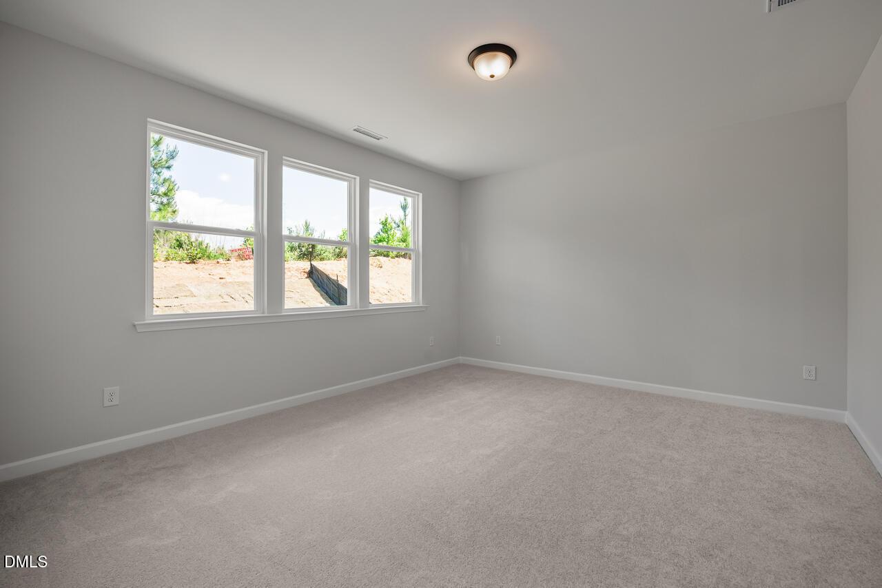Bright bedroom with neutral carpet and large windows in The Birch II E floor plan at Sage on North Main, Wake Forest, NC.